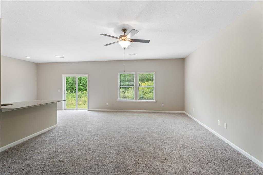 Open living area with ceiling fan, sliding doors to lush backyard, and breakfast bar in Davidson Homes The Bartlett, Phenix City, Alabama
