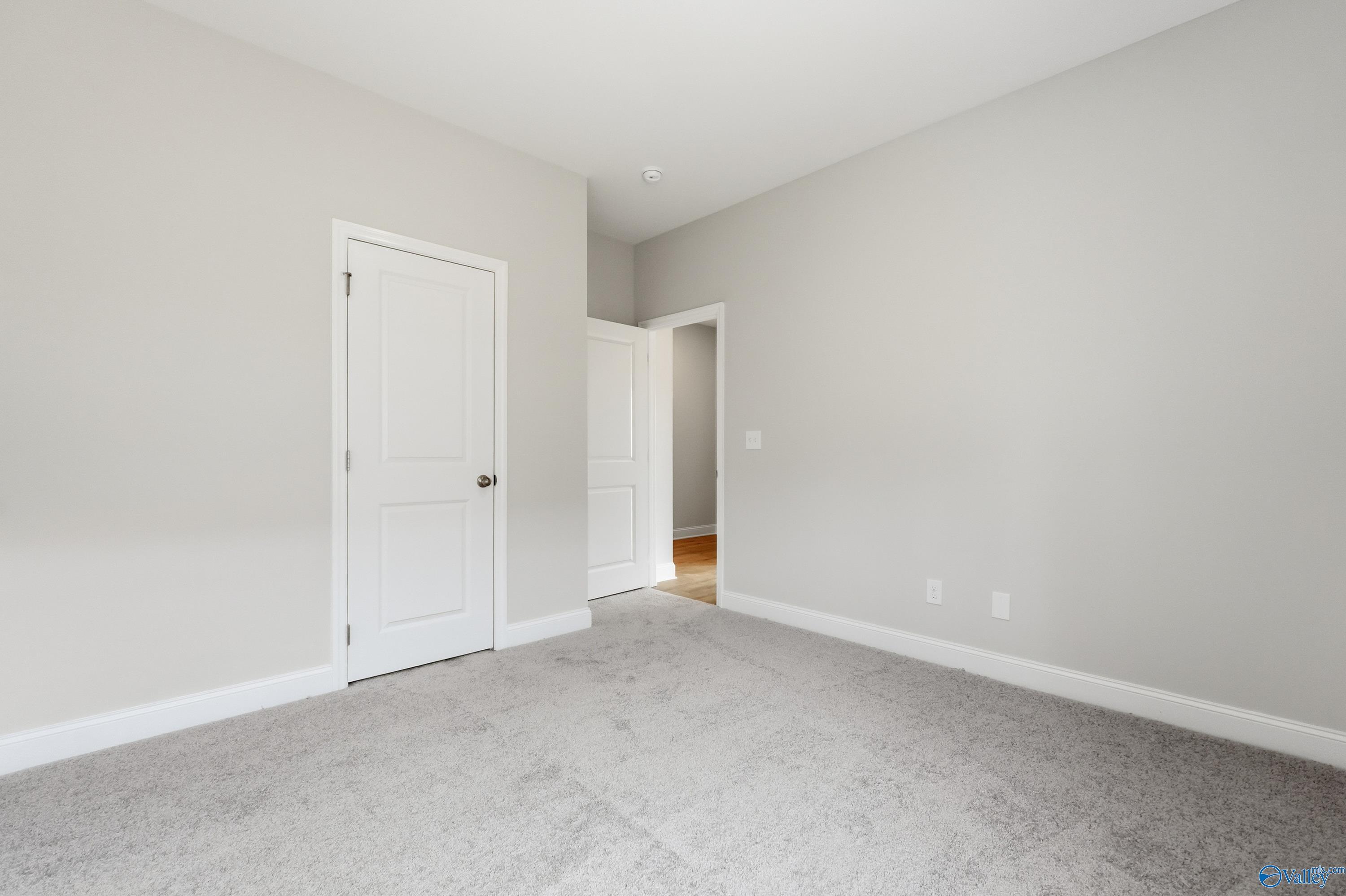 Spacious secondary bedroom featuring light gray walls, white doors, and plush carpet in Davidson Homes The Franklin, Meridianville, Alabama