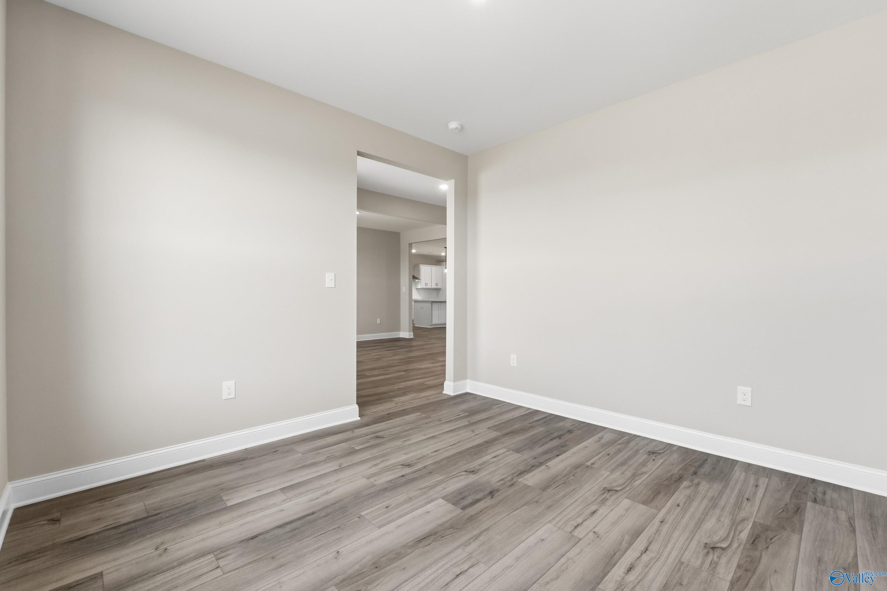 Empty bedroom featuring light gray luxury vinyl plank flooring and beige walls in Davidson Homes The Finleigh, Meridianville, Alabama