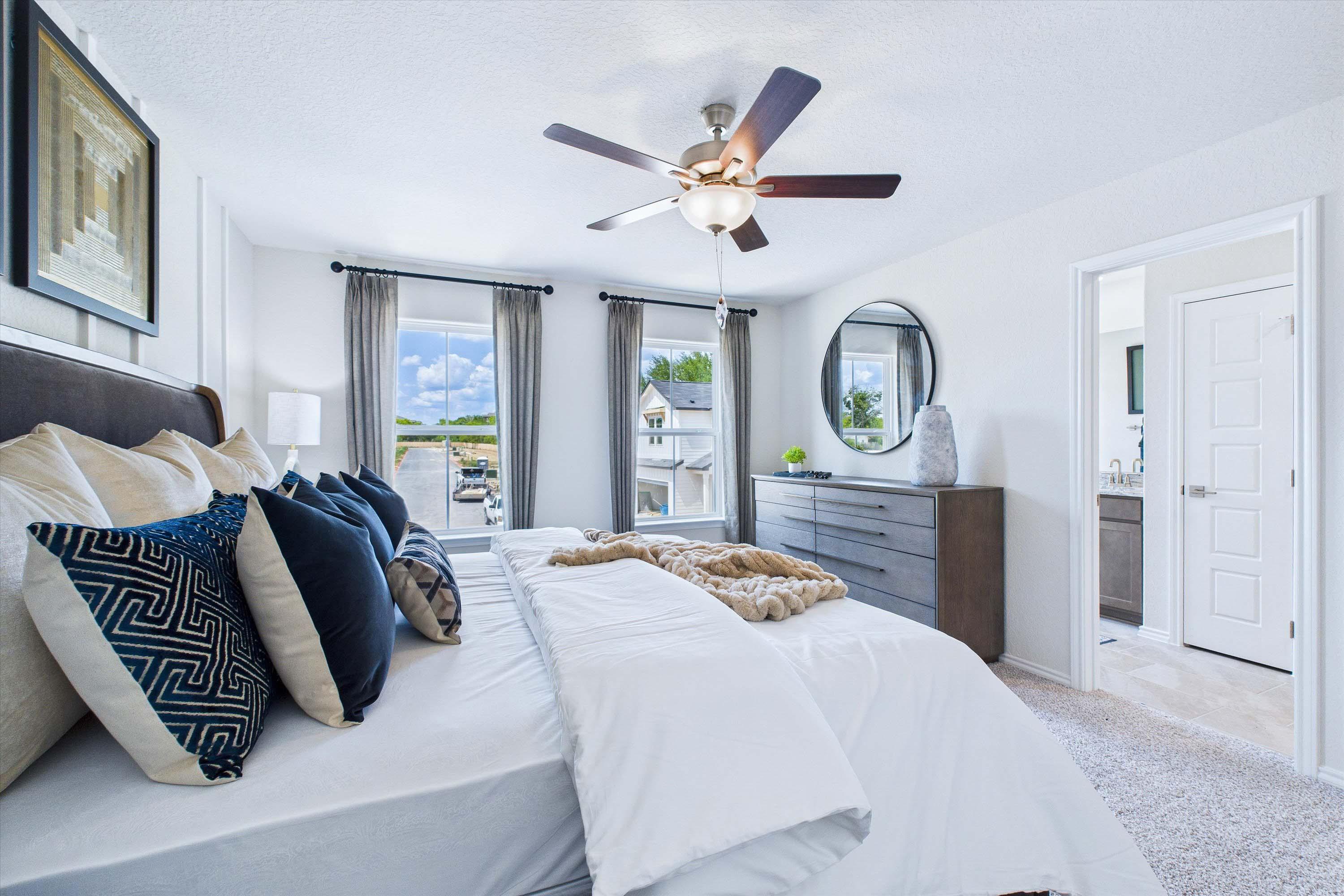 Spacious master suite in The Gillian C home design featuring stylish bedding, modern decor, and an en-suite bathroom.