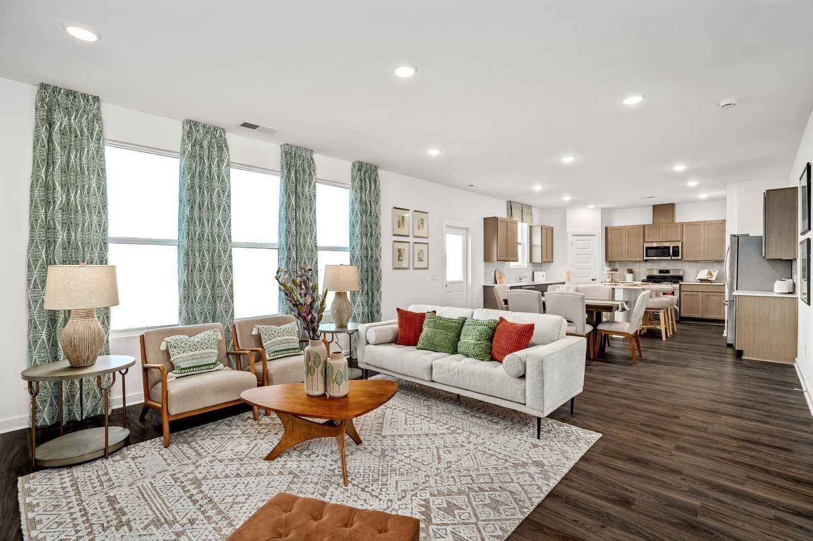 Spacious open-concept living room with modern beige sofa, wooden coffee table, and hardwood floors in Davidson Homes The Gordon C, Sage Farms, White House, Tennessee