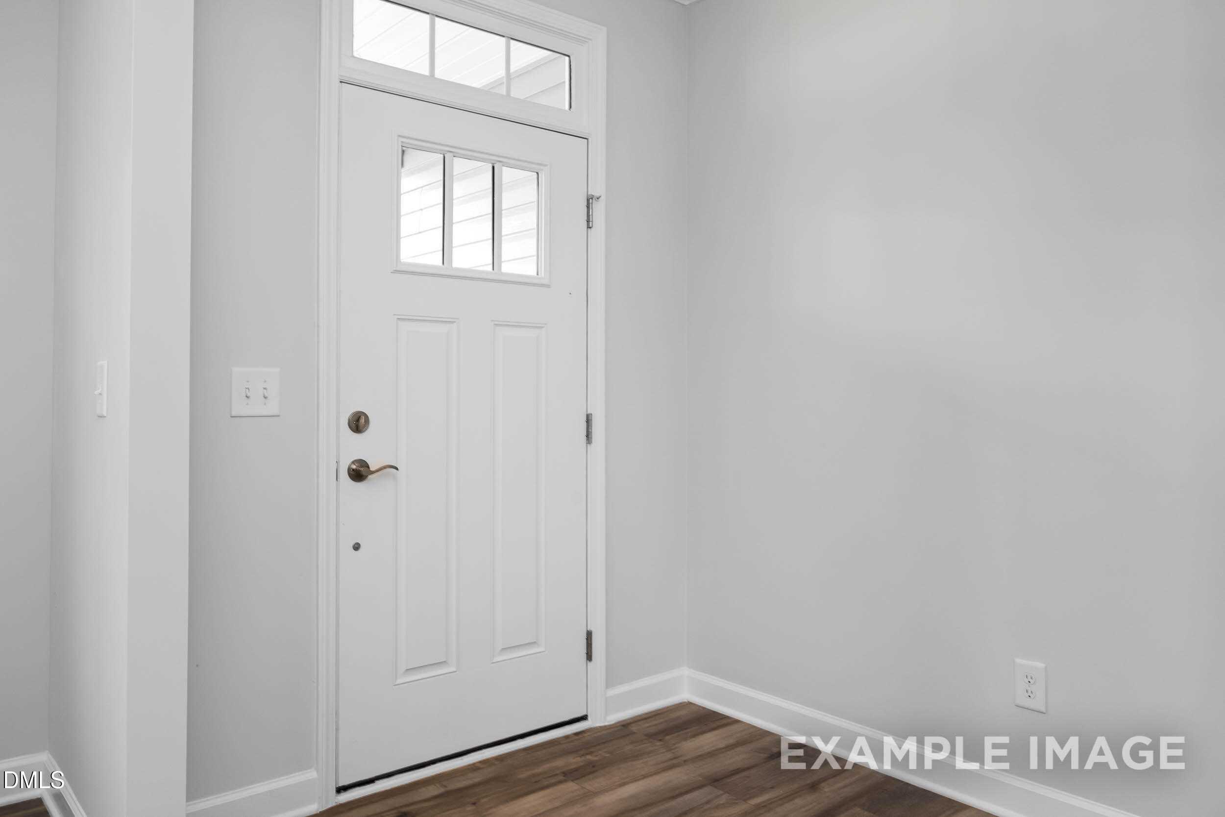 Welcoming foyer with white paneled entry door, sidelight window, gray walls, and hardwood floors in Davidson Homes The Ash B, Lillington, NC
