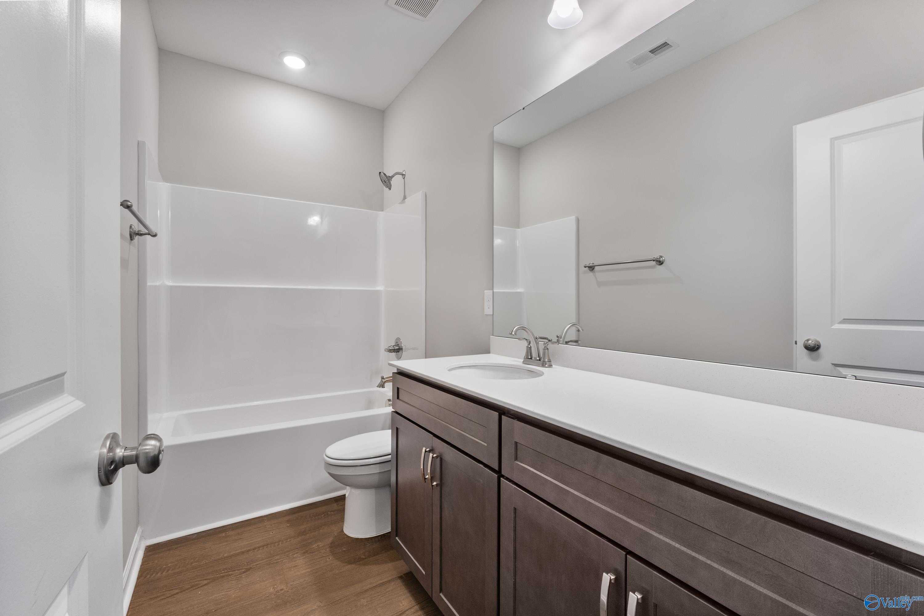 Modern secondary bathroom with tub-shower combo, single vanity, and wood flooring in Davidson Homes The Sanctuary, Huntsville