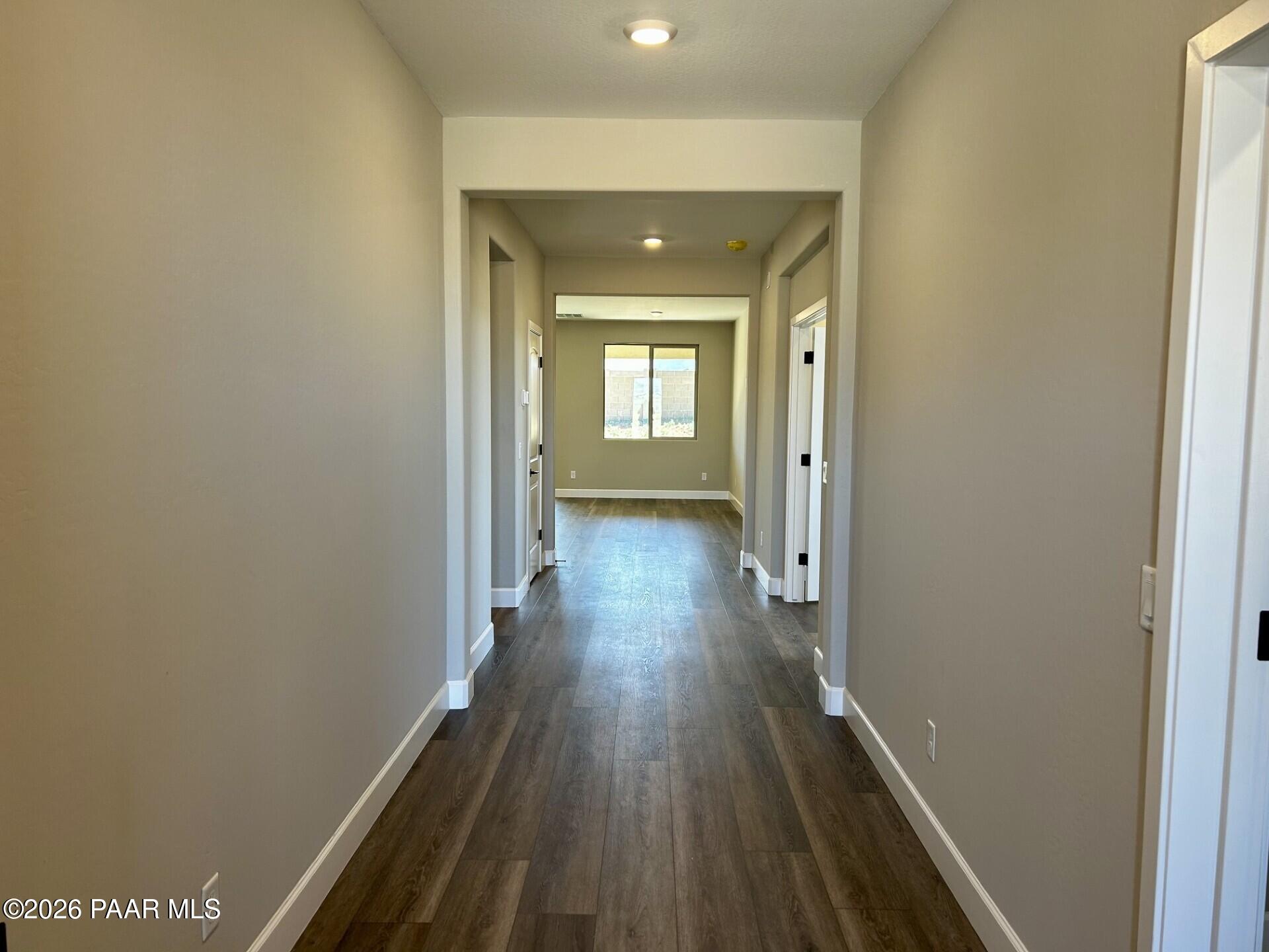 Spacious hallway with luxury vinyl plank flooring, neutral beige walls, and open doorways in Davidson Homes The Harmony C, Prescott Valley, AZ
