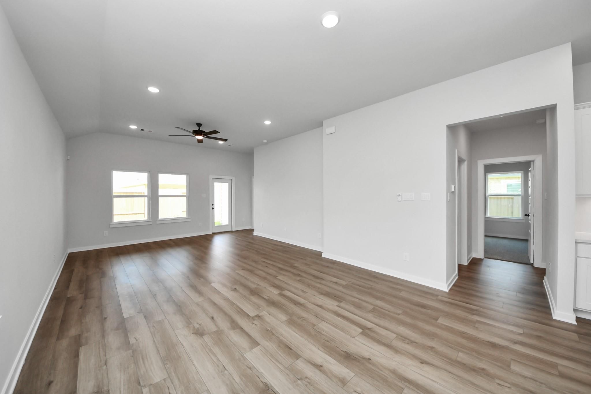 Spacious open-concept living area with wood-look flooring in The Riviera C floor plan, River Ranch Meadows, Dayton, Texas.