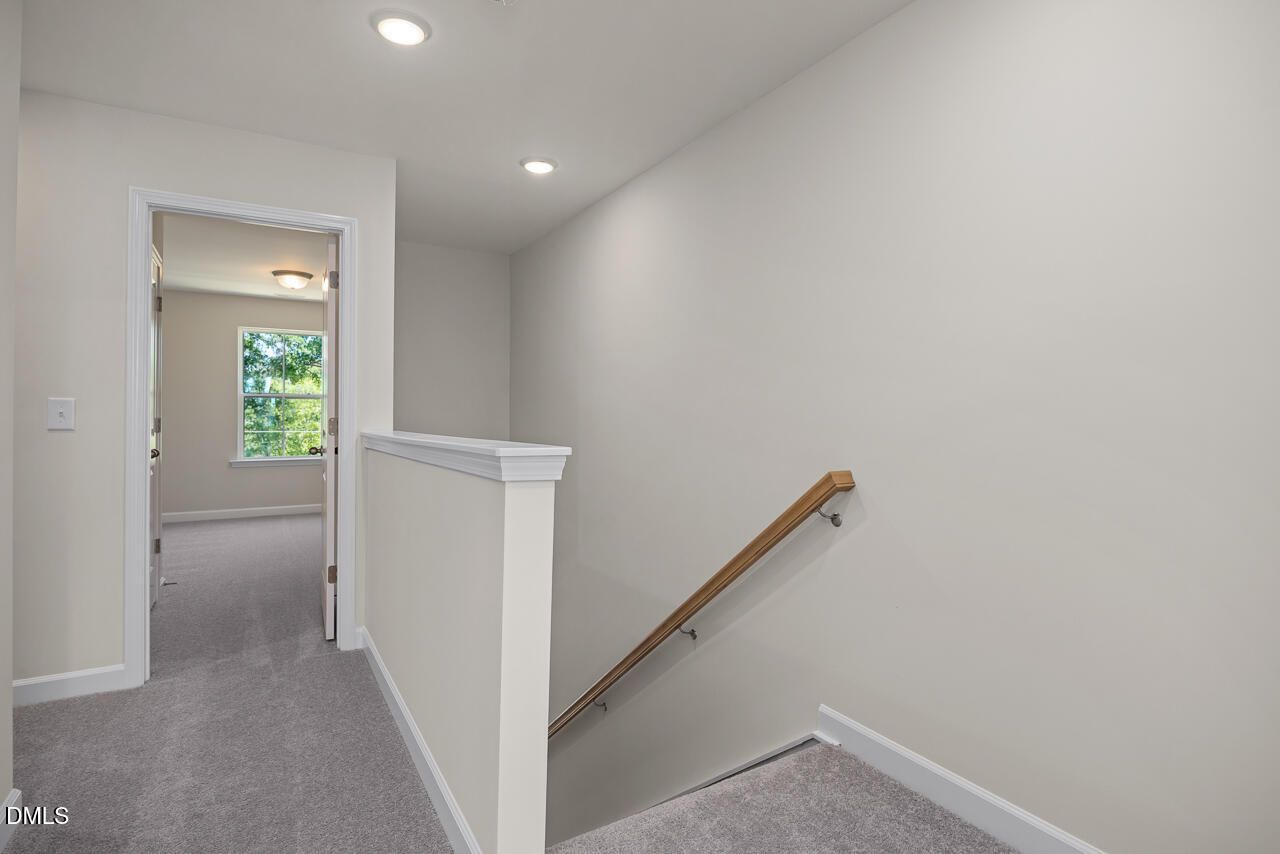Bright carpeted hallway with wooden handrail leading to a bedroom in The Mitchell Interior floor plan, Camden Park.