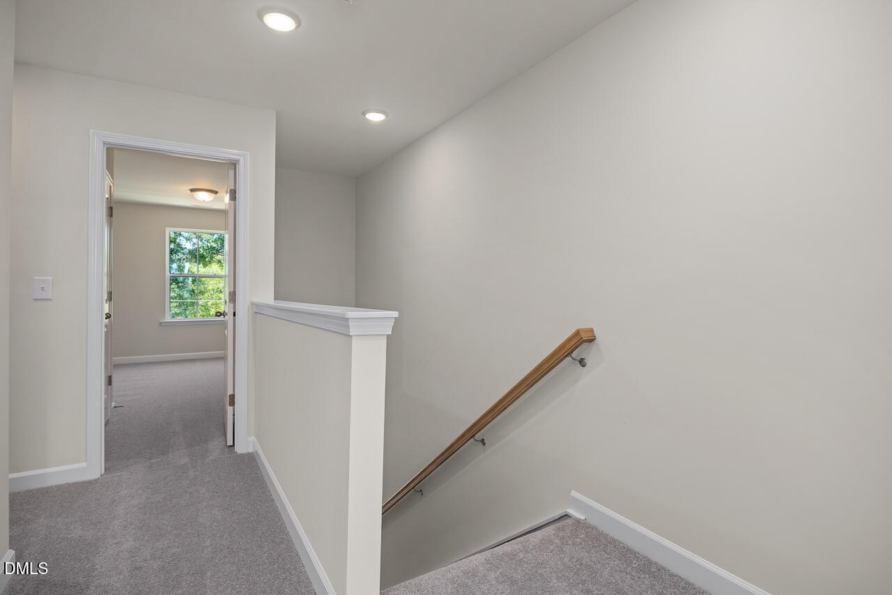 Bright carpeted hallway with wooden handrail leading to a bedroom in The Mitchell Interior floor plan, Camden Park.