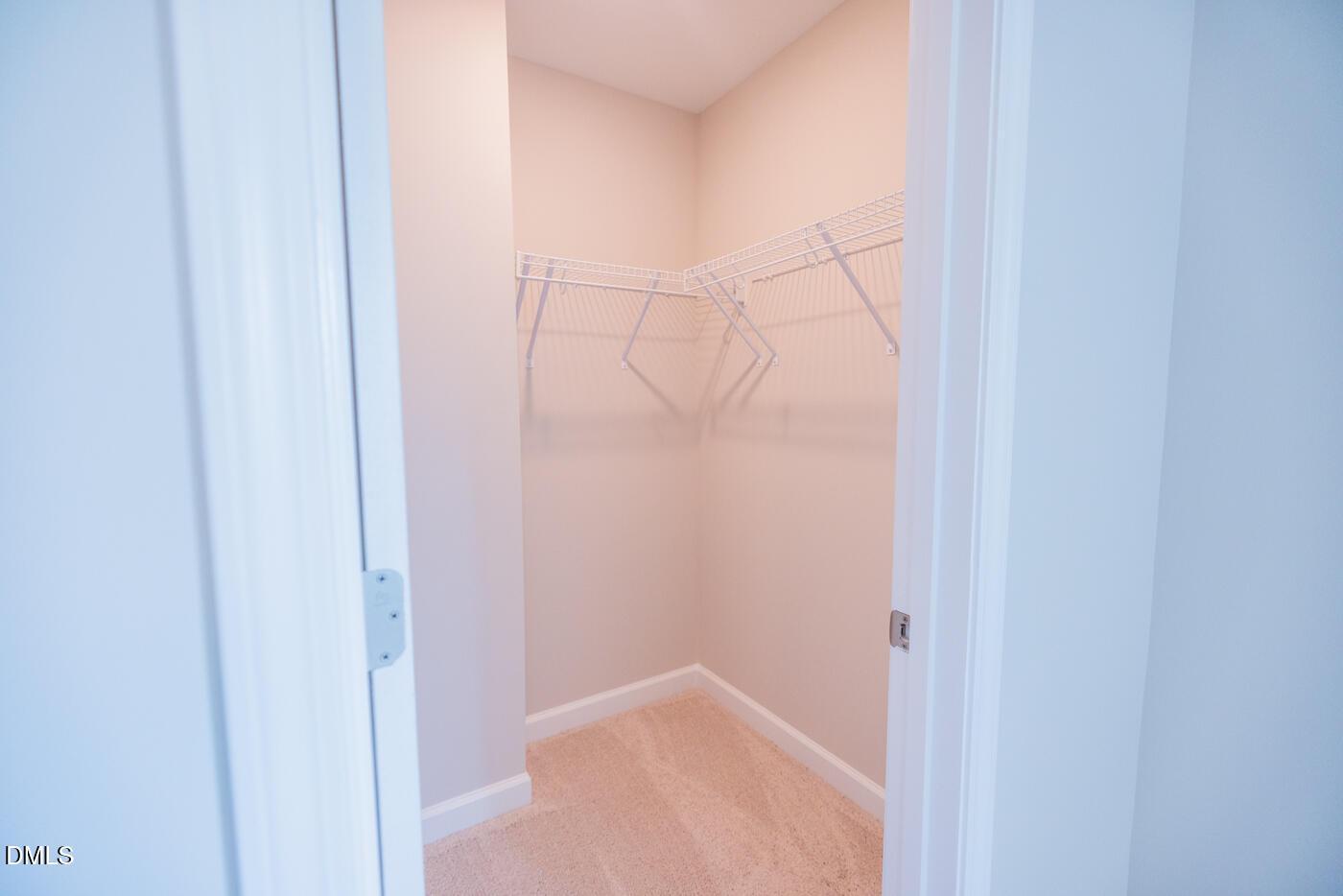 Spacious walk-in closet with wire shelving, beige walls, and hardwood floors in The Hickory II C by Davidson Homes, Zebulon, NC