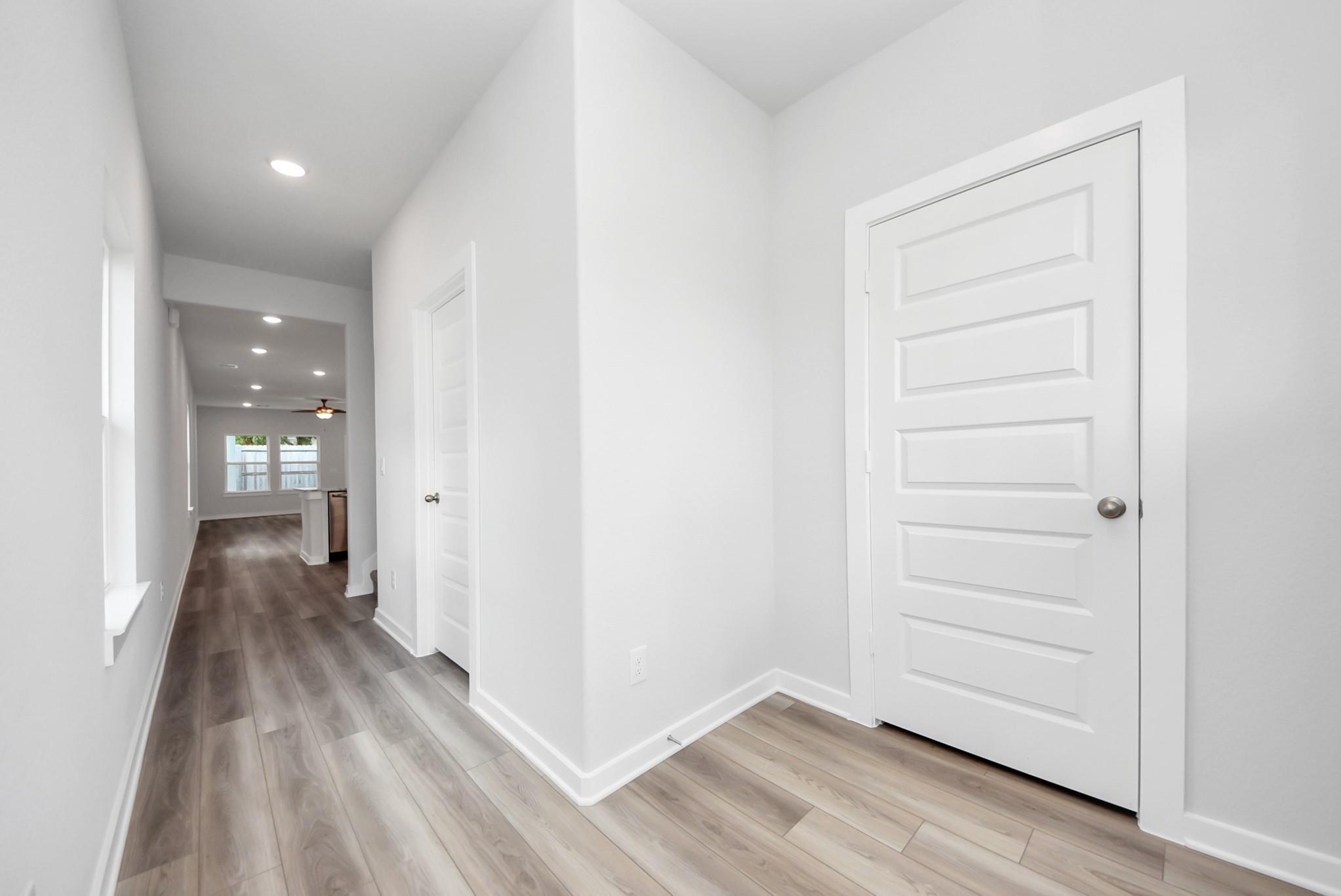 Bright hallway with wood-look flooring leading to open living area in Davidson Homes Sabine E floor plan, Magnolia, TX.