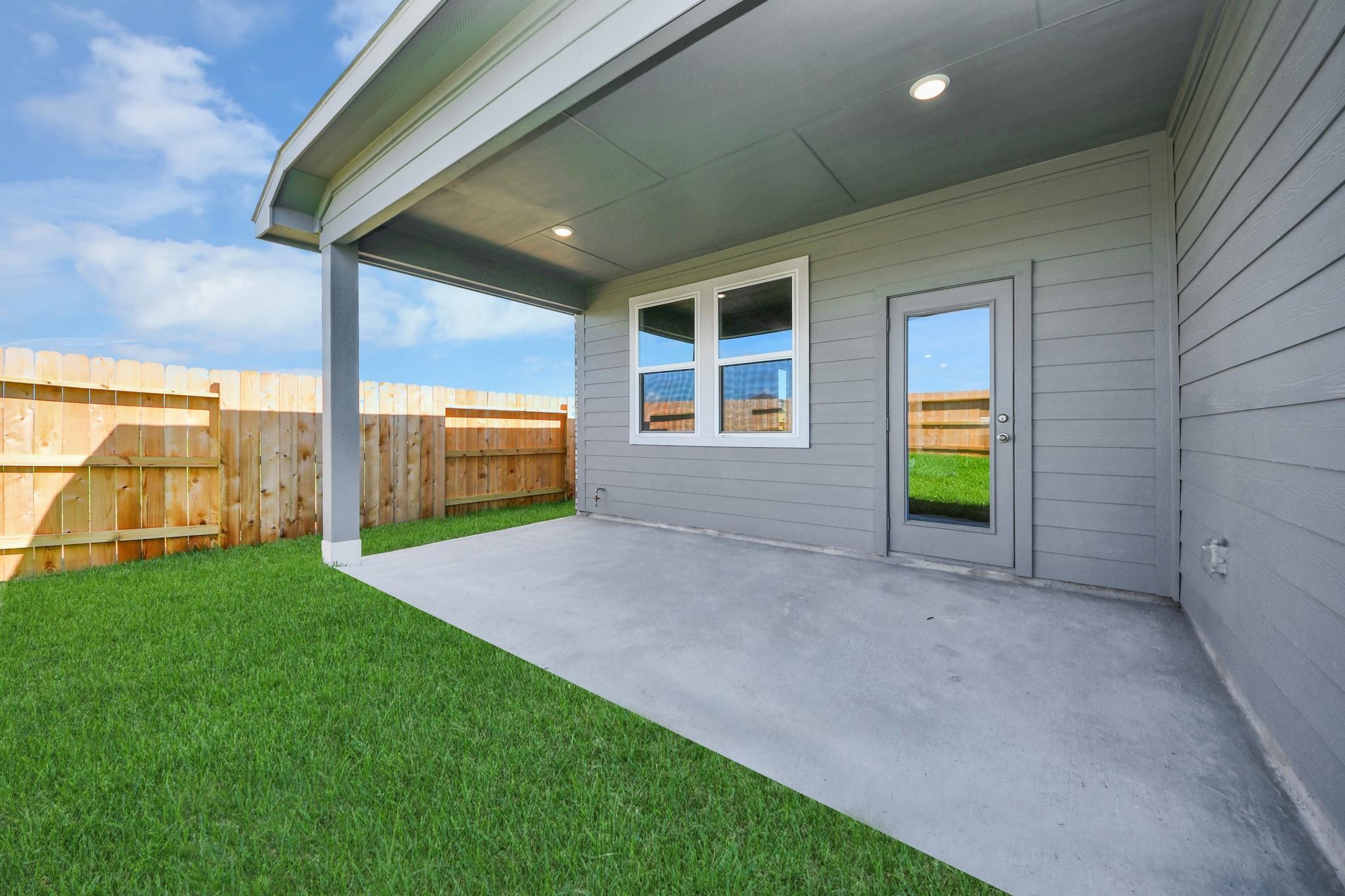 Covered concrete patio with recessed lighting in the backyard of a Riviera A floor plan home in Emberly, Beasley, Texas.