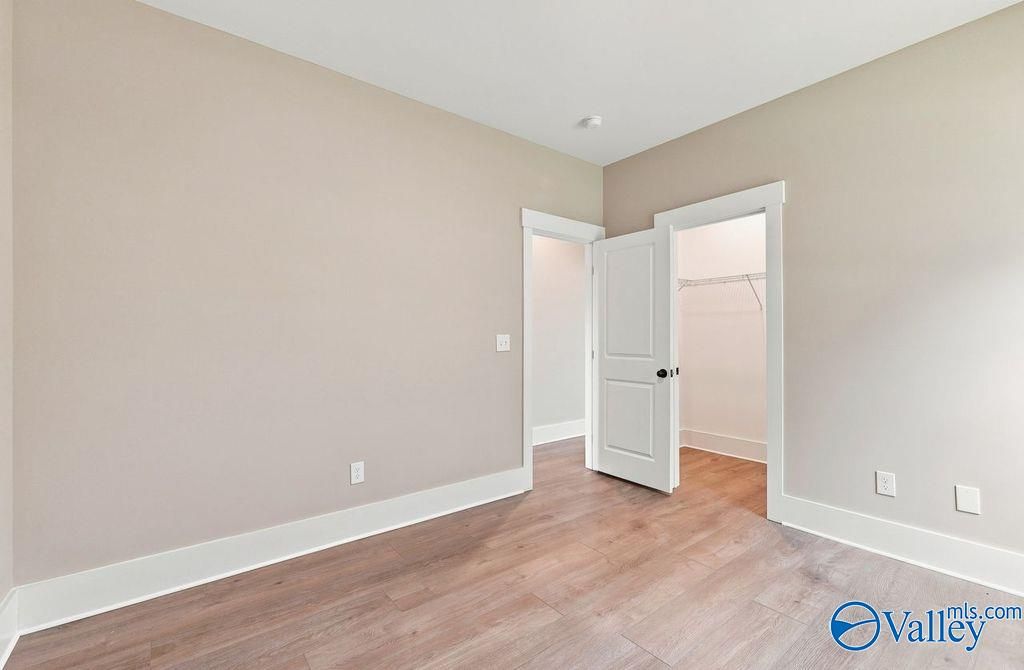 Spacious secondary bedroom with wood-style flooring and walk-in closet in The Rockford floor plan, Cain Park, Hartselle, AL.