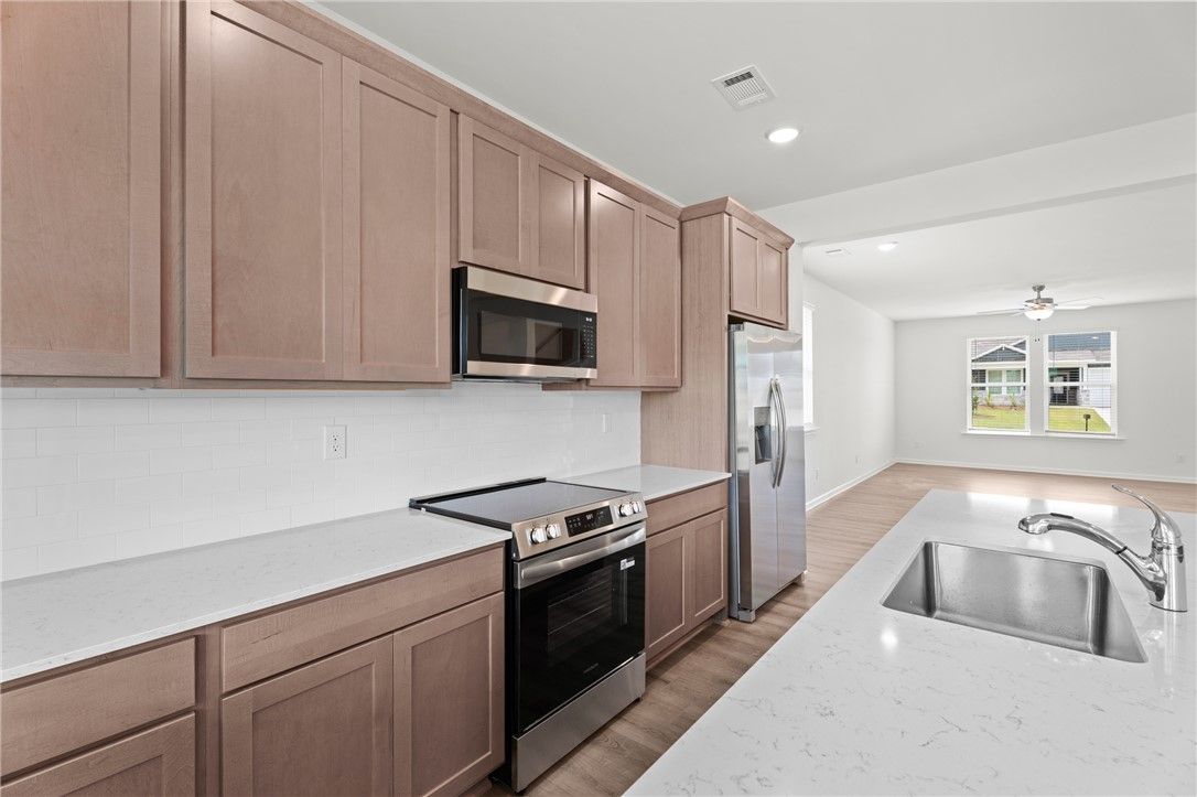 Modern kitchen with quartz countertops and stainless appliances in The Stella D floor plan by Evermore Homes in Cusseta.