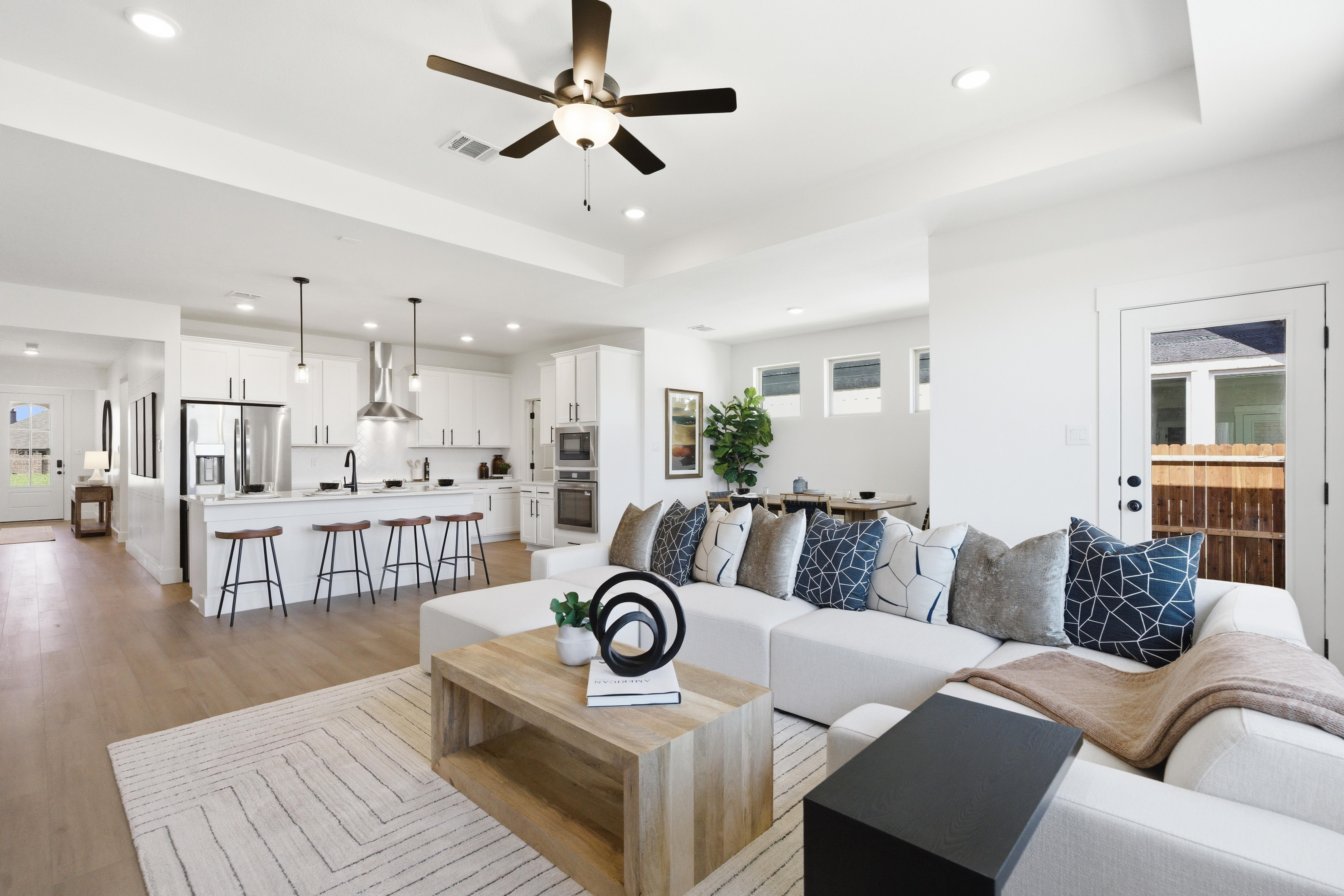Open-concept kitchen and living area in Mercer Meadows, Royse City, TX with white cabinetry, hardwood floors, sectional sofa