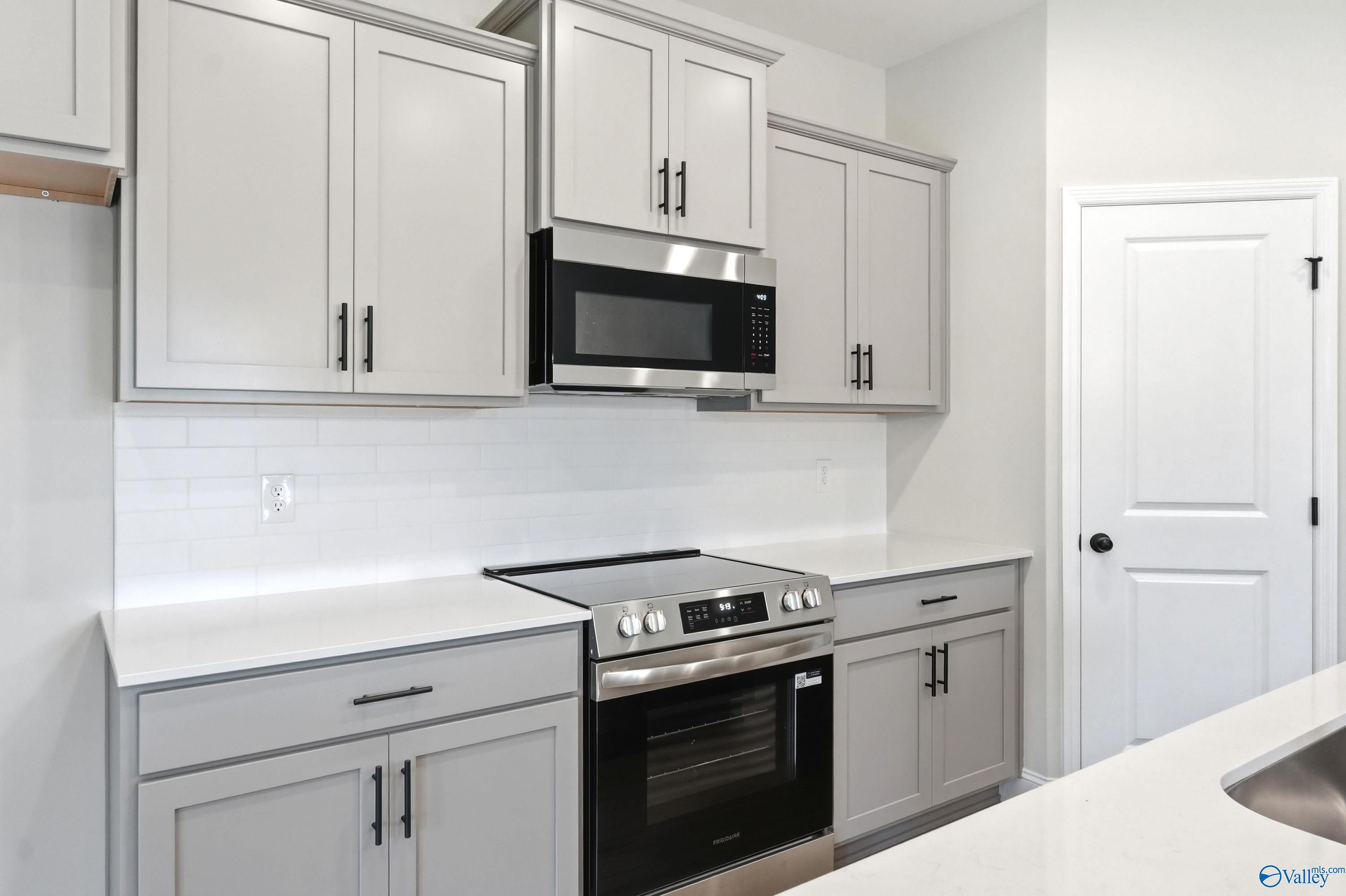 Modern kitchen with gray cabinets, white countertops, and stainless appliances in The Russell A plan, Huntsville, Alabama.