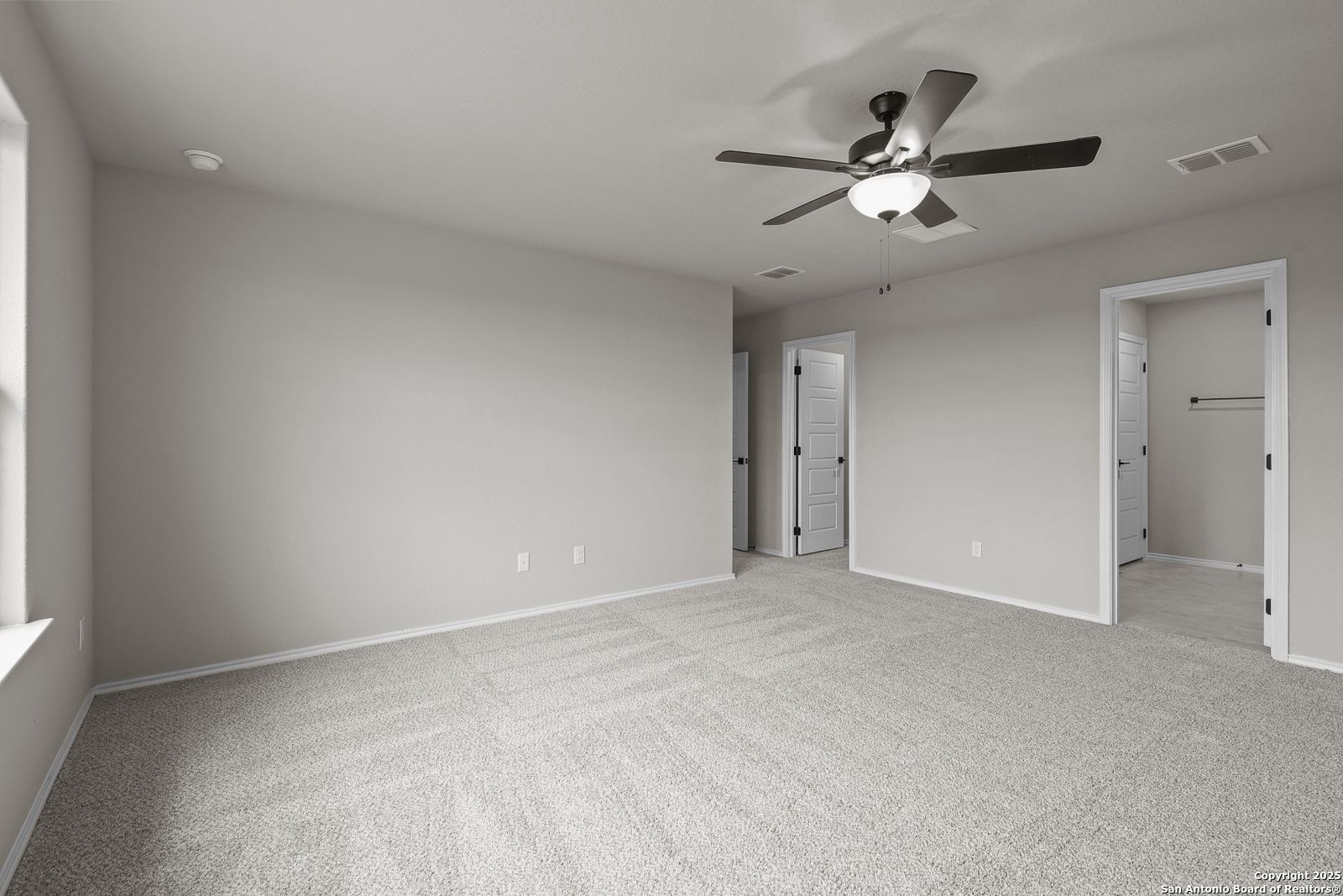 Spacious secondary bedroom with ceiling fan, walk-in closet, and gray carpet in Davidson Homes The Murray J, San Antonio