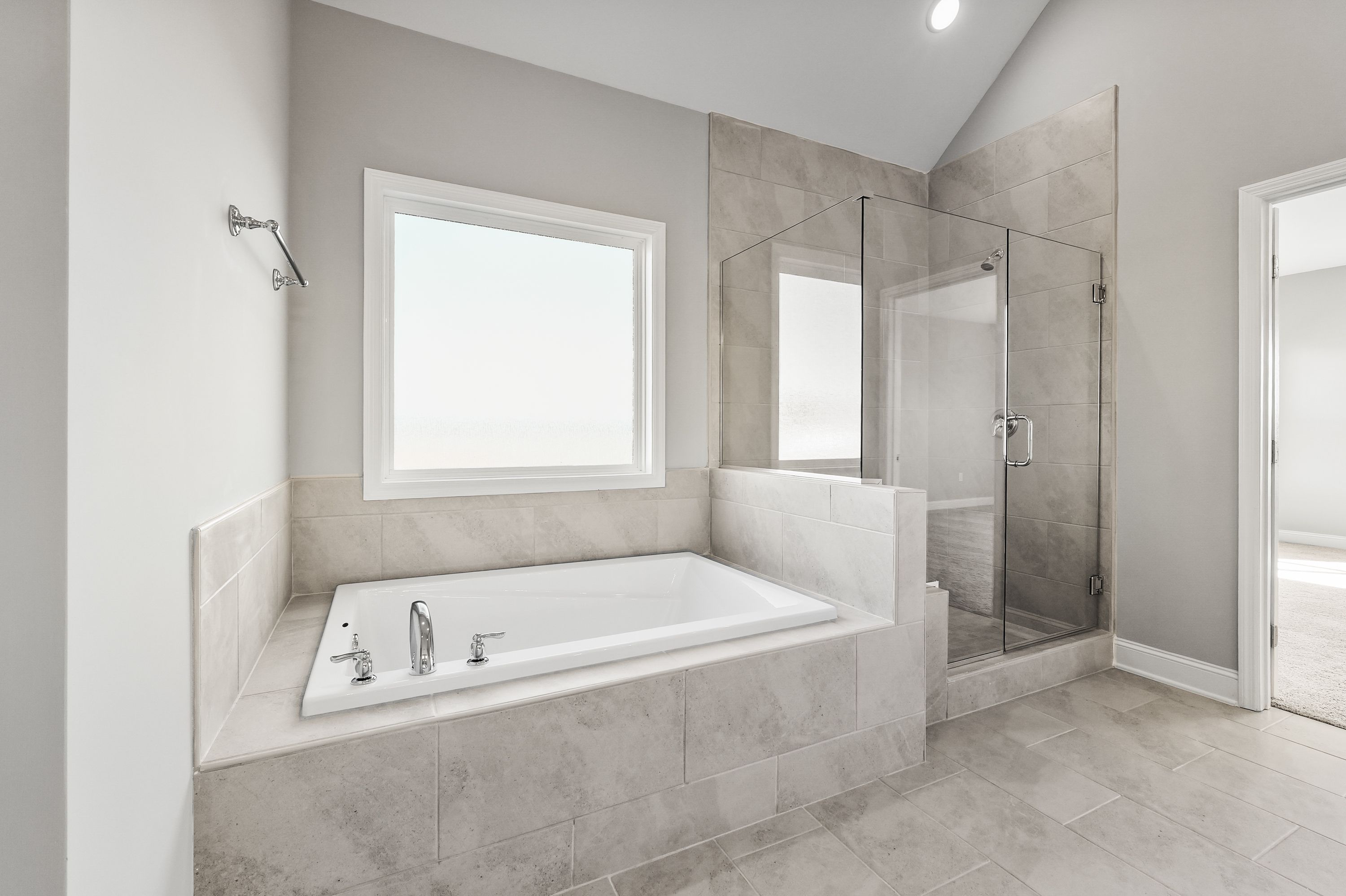 Luxurious master bathroom in The Valencia by Davidson Homes with freestanding tub, glass shower, and tiled accents