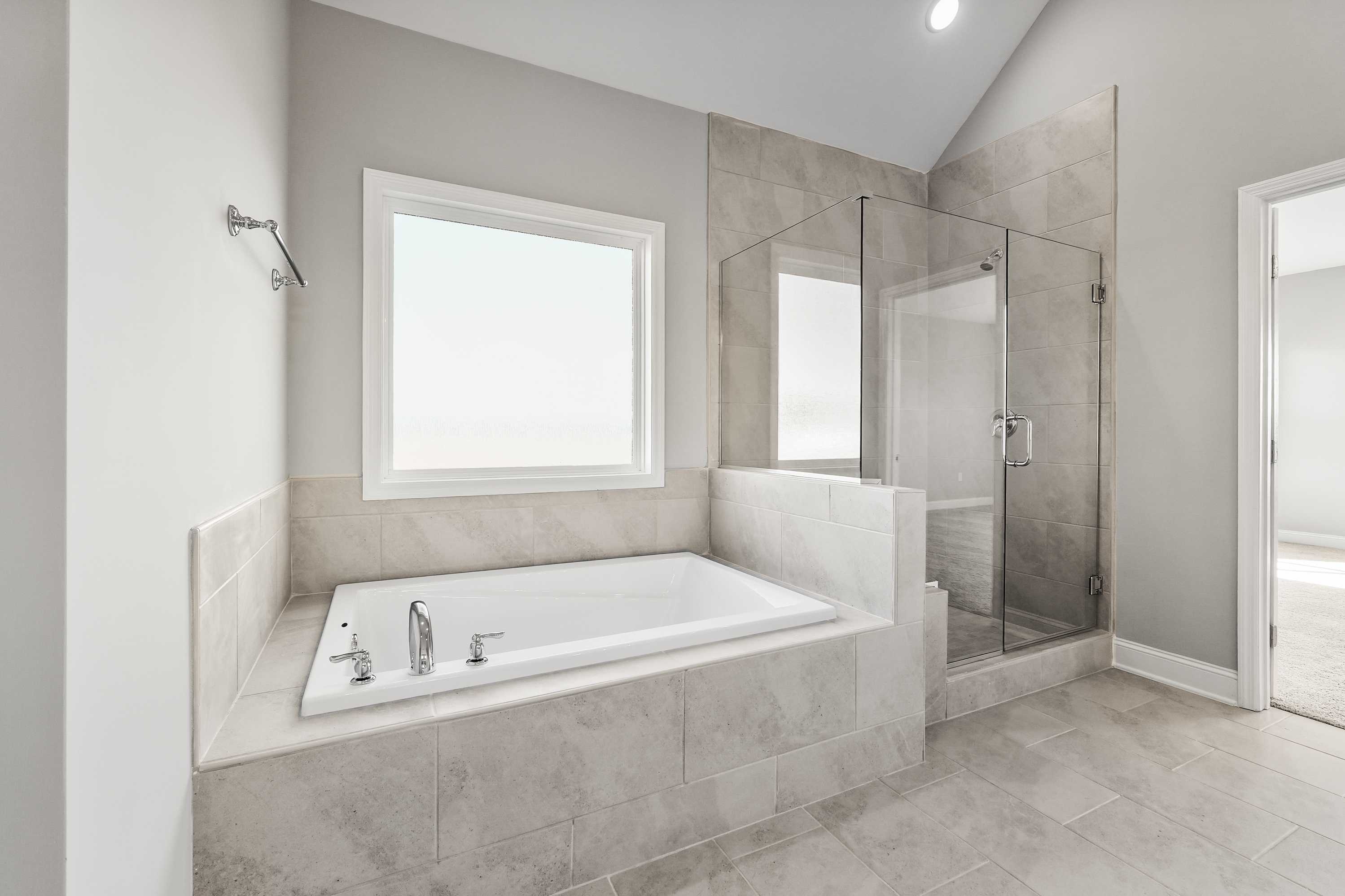 Luxurious master bathroom in The Valencia by Davidson Homes with freestanding tub, glass shower, and tiled accents