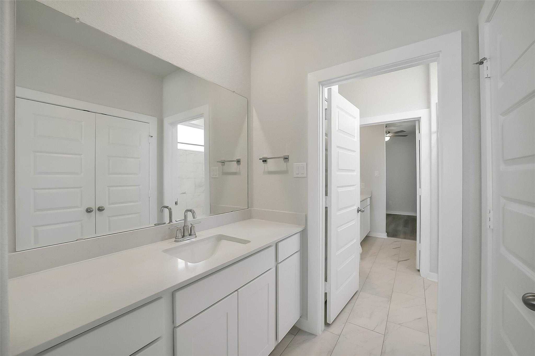 Modern white quartz vanity with undermount sink and large mirror in Davidson Homes The Acadia A bathroom, Katy Texas