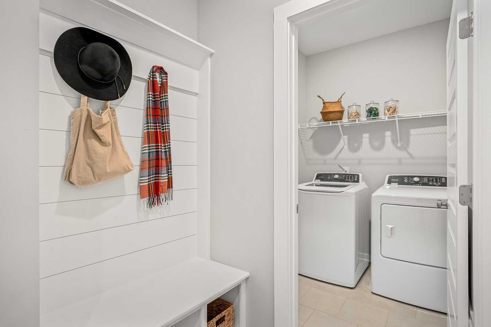 Spacious laundry room at Sage Farms in White House TN with shiplap walls, washer dryer, mudroom bench and storage hooks
