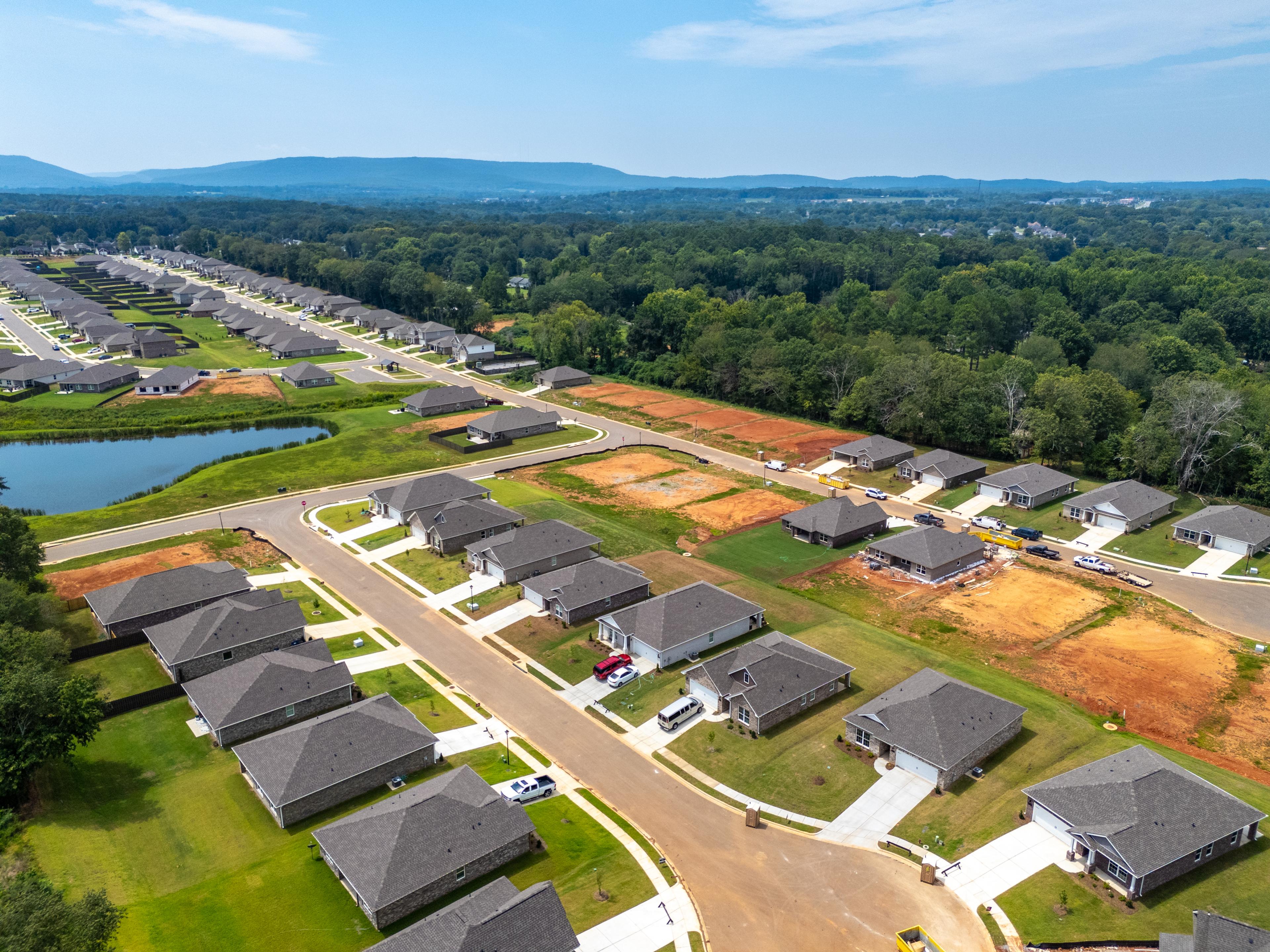 Aerial view of new homes under construction at Flint Meadows in New Market, Alabama by Davidson Homes with pond and wooded hills