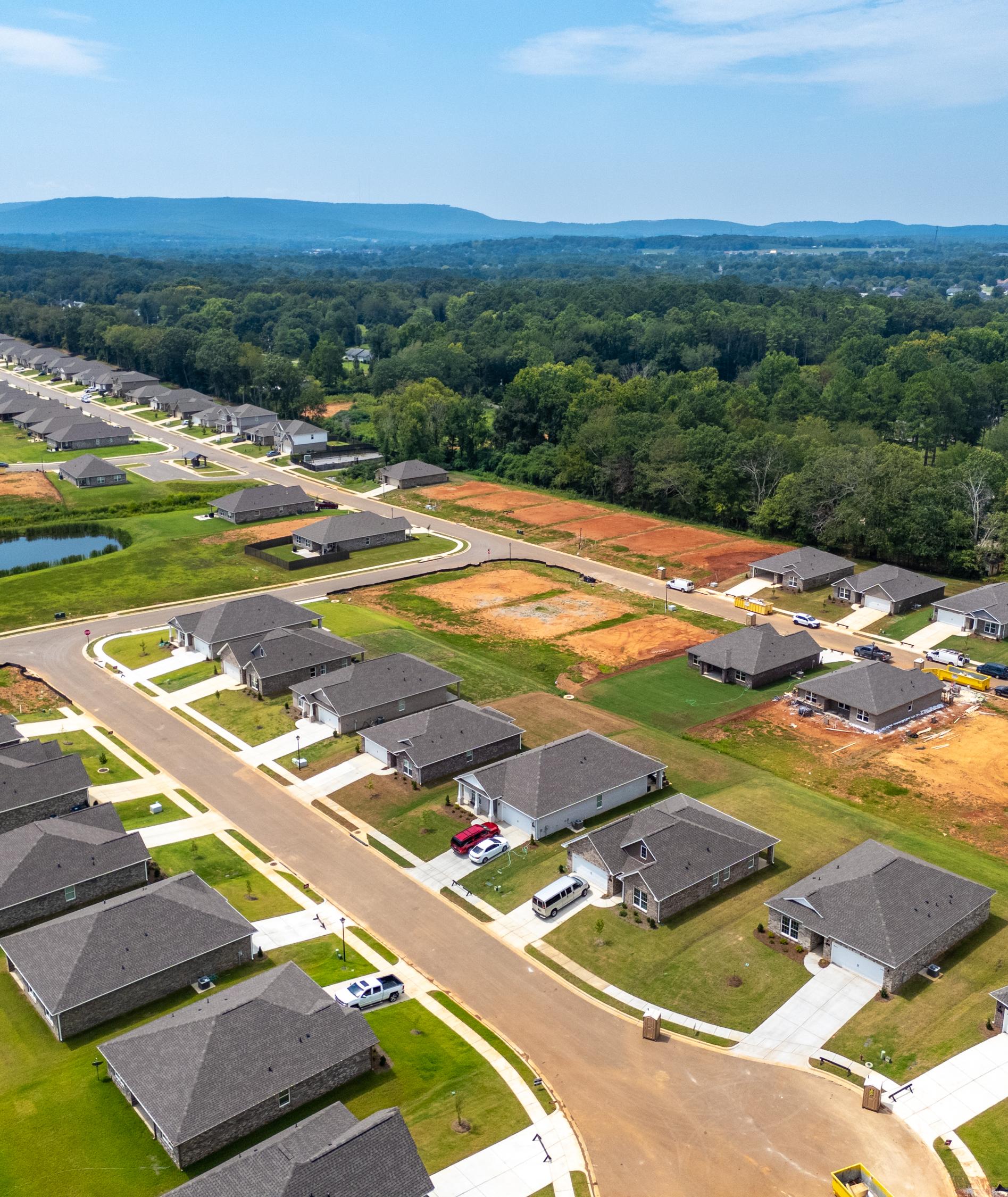 Aerial view of new homes under construction at Flint Meadows in New Market, Alabama by Davidson Homes with pond and wooded hills