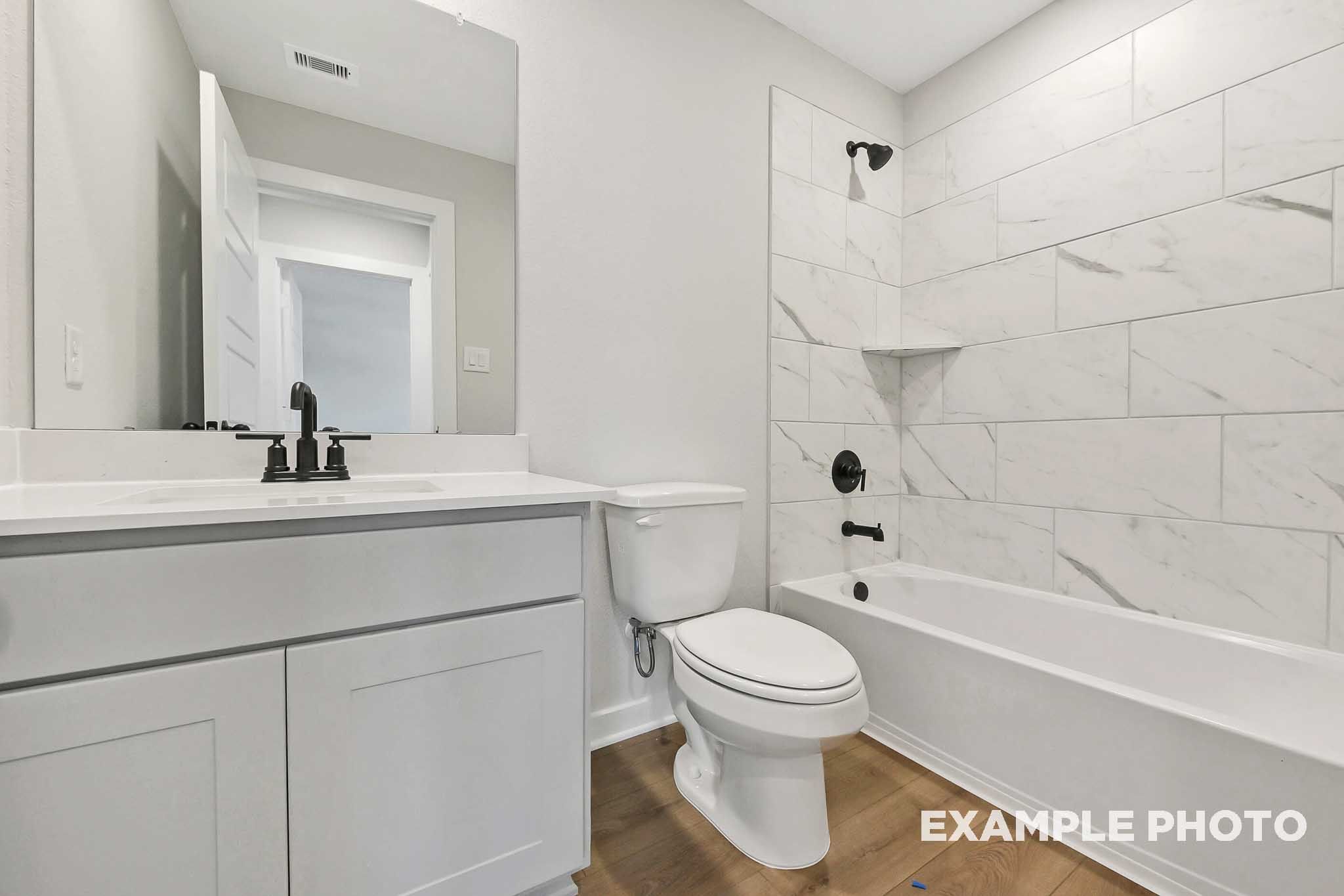 Spacious master bathroom in The Sequoia with white subway tile shower, soaking tub, modern vanity, and hardwood floors
