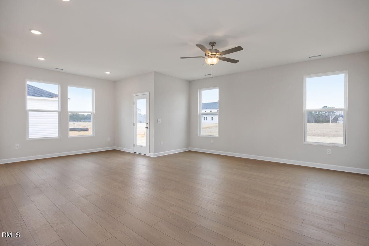 Spacious living room with large windows, ceiling fan, and hardwood floors in Davidson Homes The Daphne C, Lillington NC