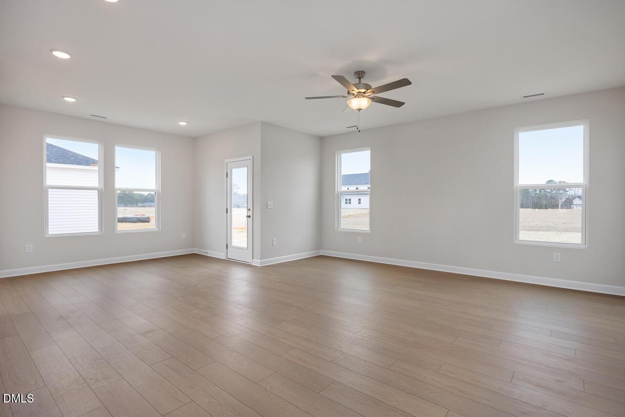 Spacious living room with large windows, ceiling fan, and hardwood floors in Davidson Homes The Daphne C, Lillington NC