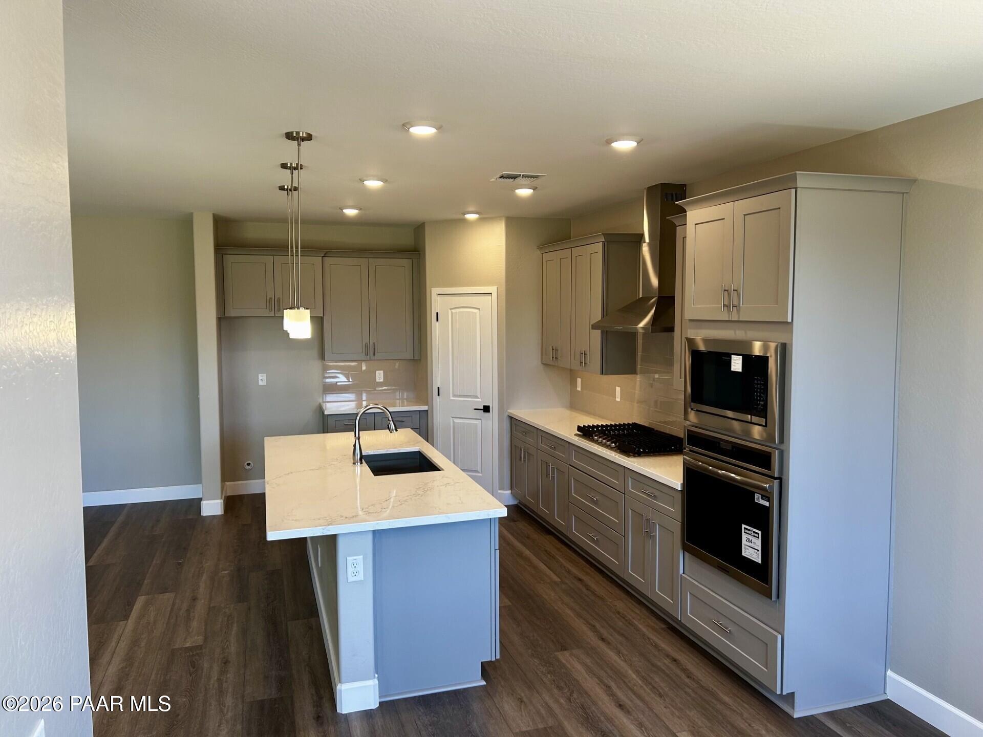 Modern kitchen with quartz island, grey cabinets, and stainless appliances in Harmony C home at Pronghorn Ranch, Prescott.