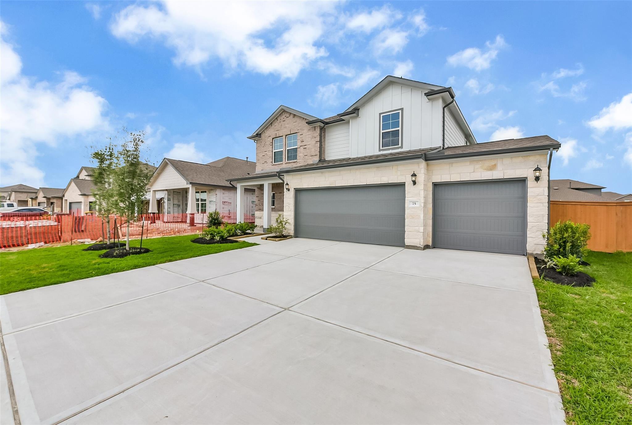 Modern two-story home with 3-car garage, stone and brick facade, landscaped yard in River Ranch Meadows, Dayton, Texas by Davidson Homes