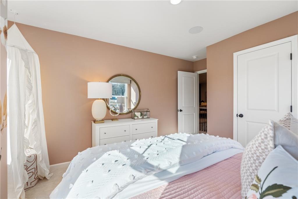 Serene beige bedroom with tufted white bed, round mirror on dresser, sheer curtains in Davidson Homes The Marion B, Kennesaw, GA