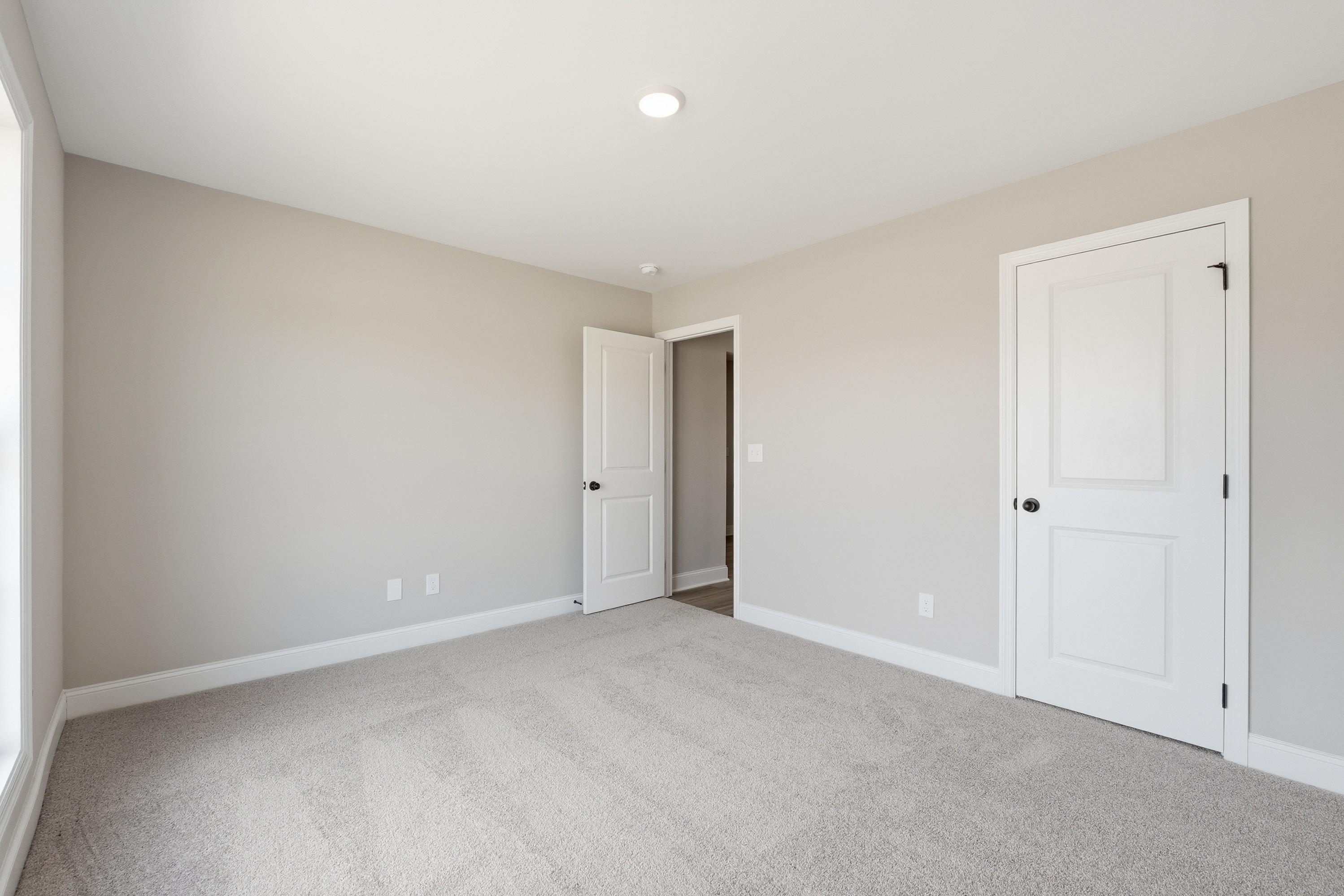 Spacious secondary bedroom in The Daphne V with beige walls, carpet flooring, white doors, and window light