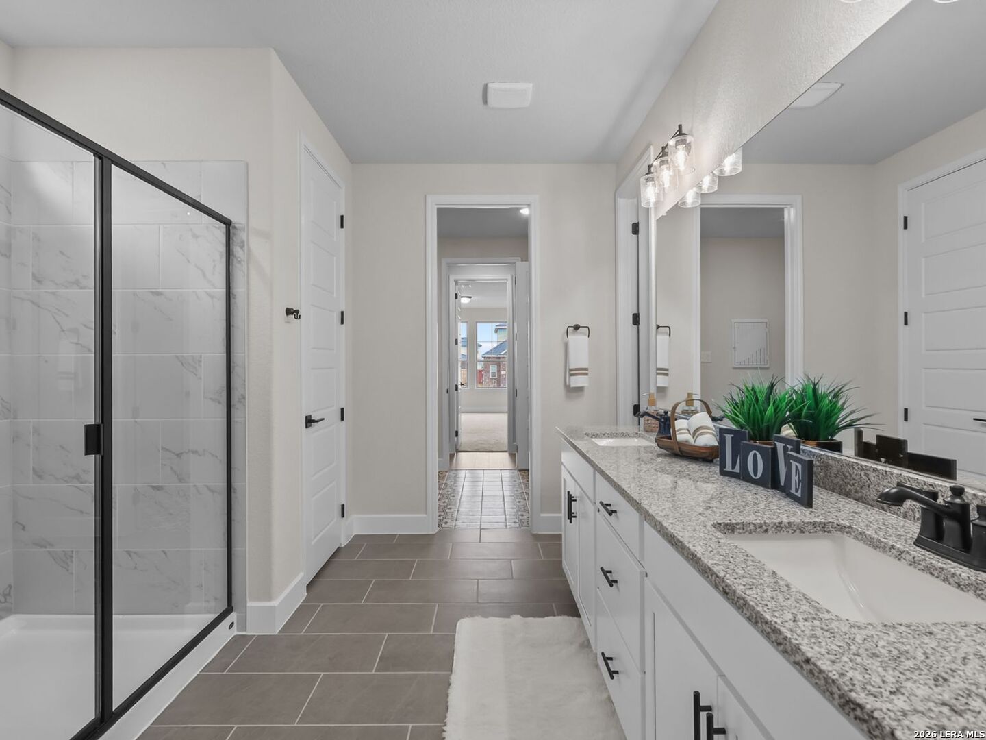 Modern bathroom with dual vanity, granite countertops, and glass shower in a Davidson Homes Belmont H plan in Castroville, TX.