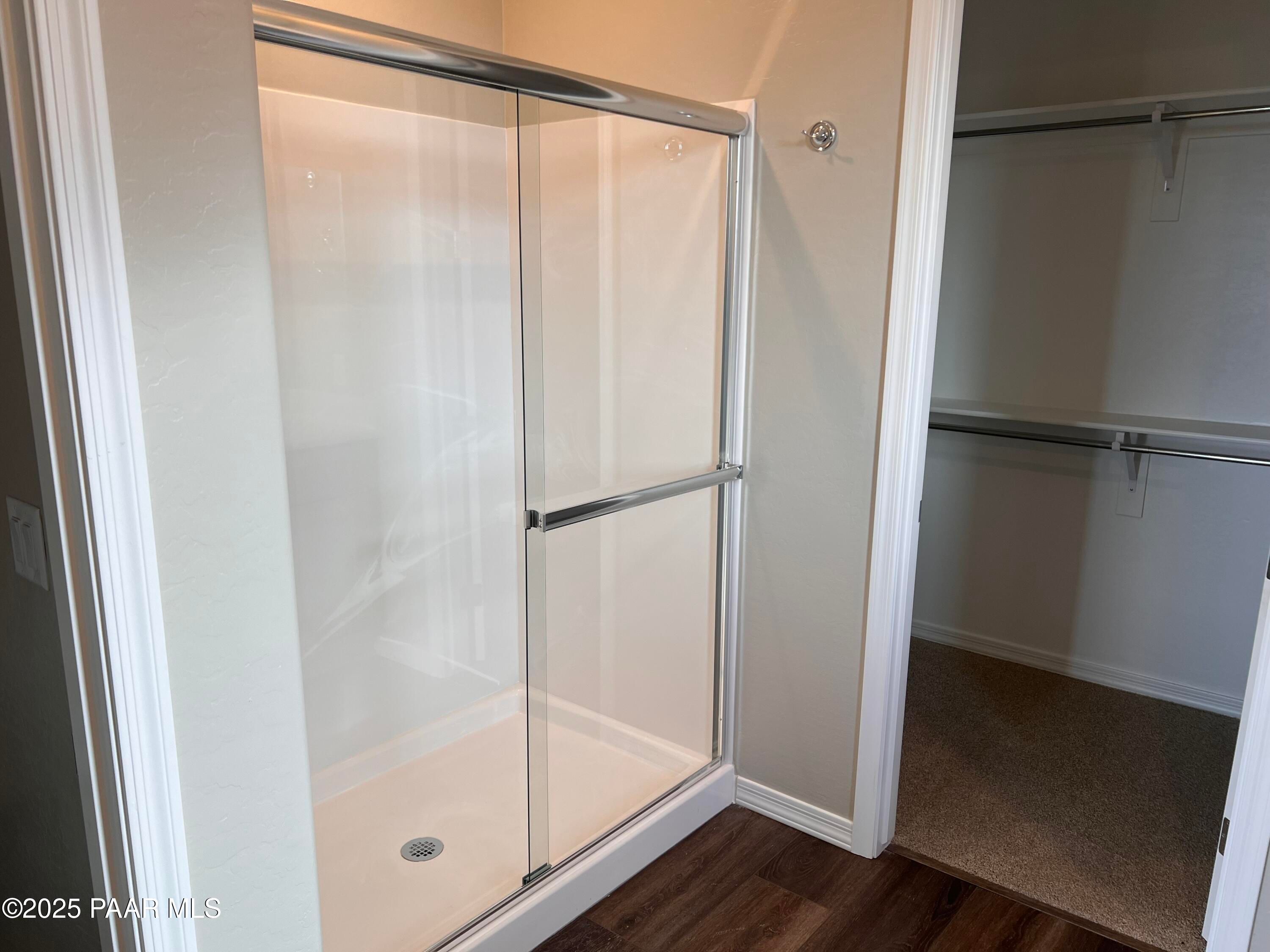 Modern walk-in glass shower with white tile and adjacent closet in master bath of Davidson Homes The Frontier A, Prescott Valley, AZ