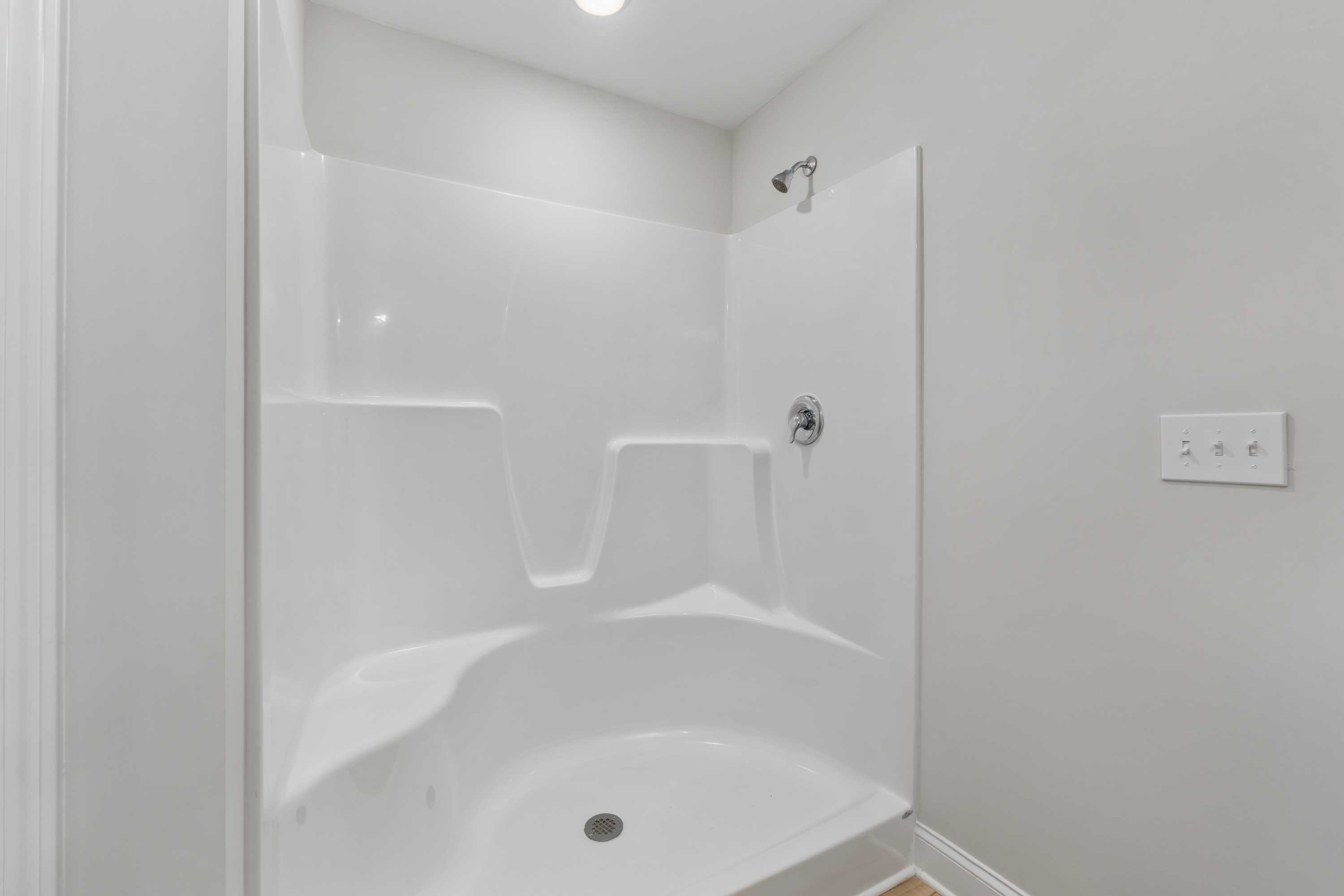 Modern white corner shower with glass door in Collins Lane home, Meridianville Alabama by Davidson Homes