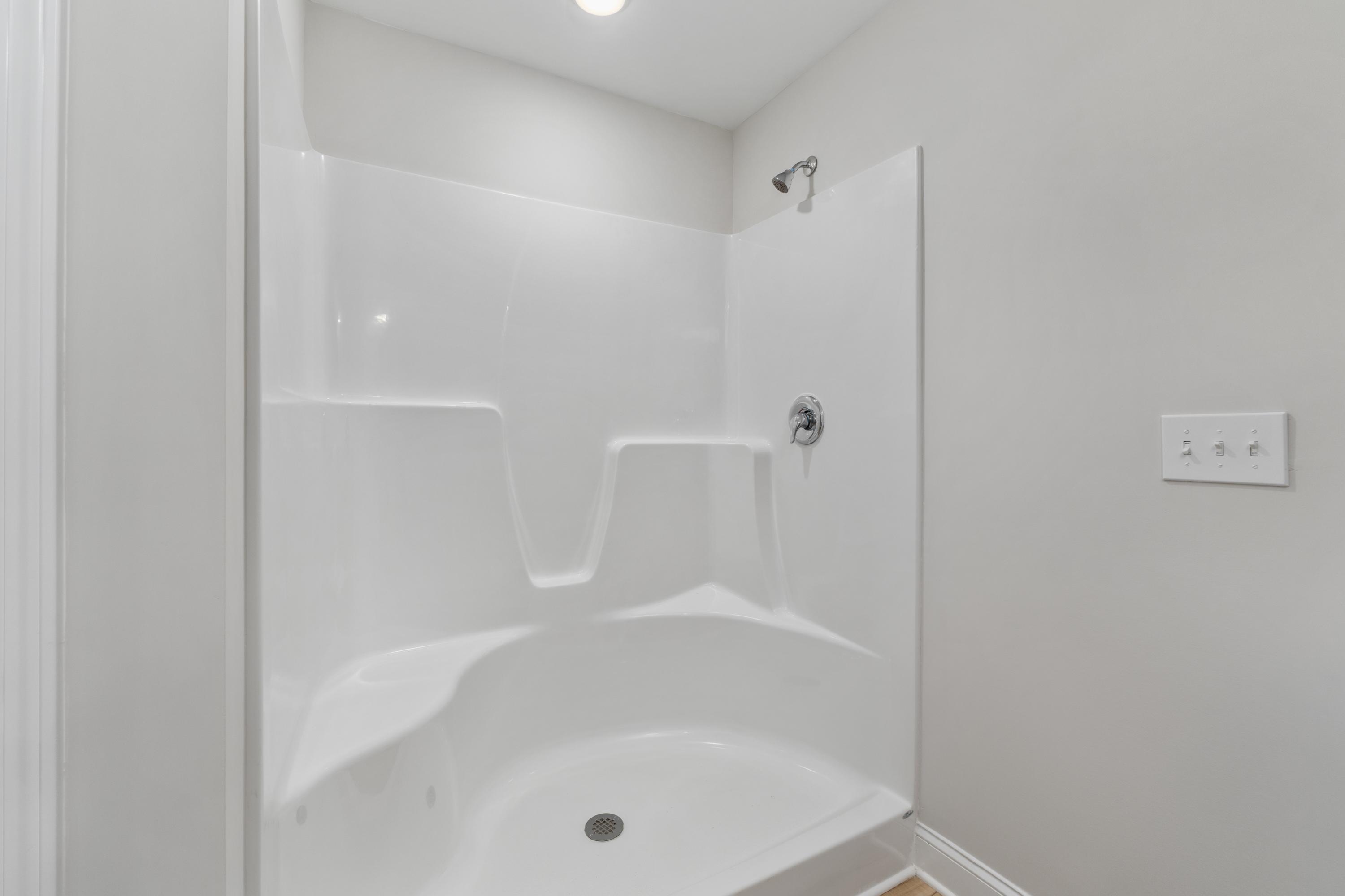 Modern white corner shower with glass door in Collins Lane home, Meridianville Alabama by Davidson Homes
