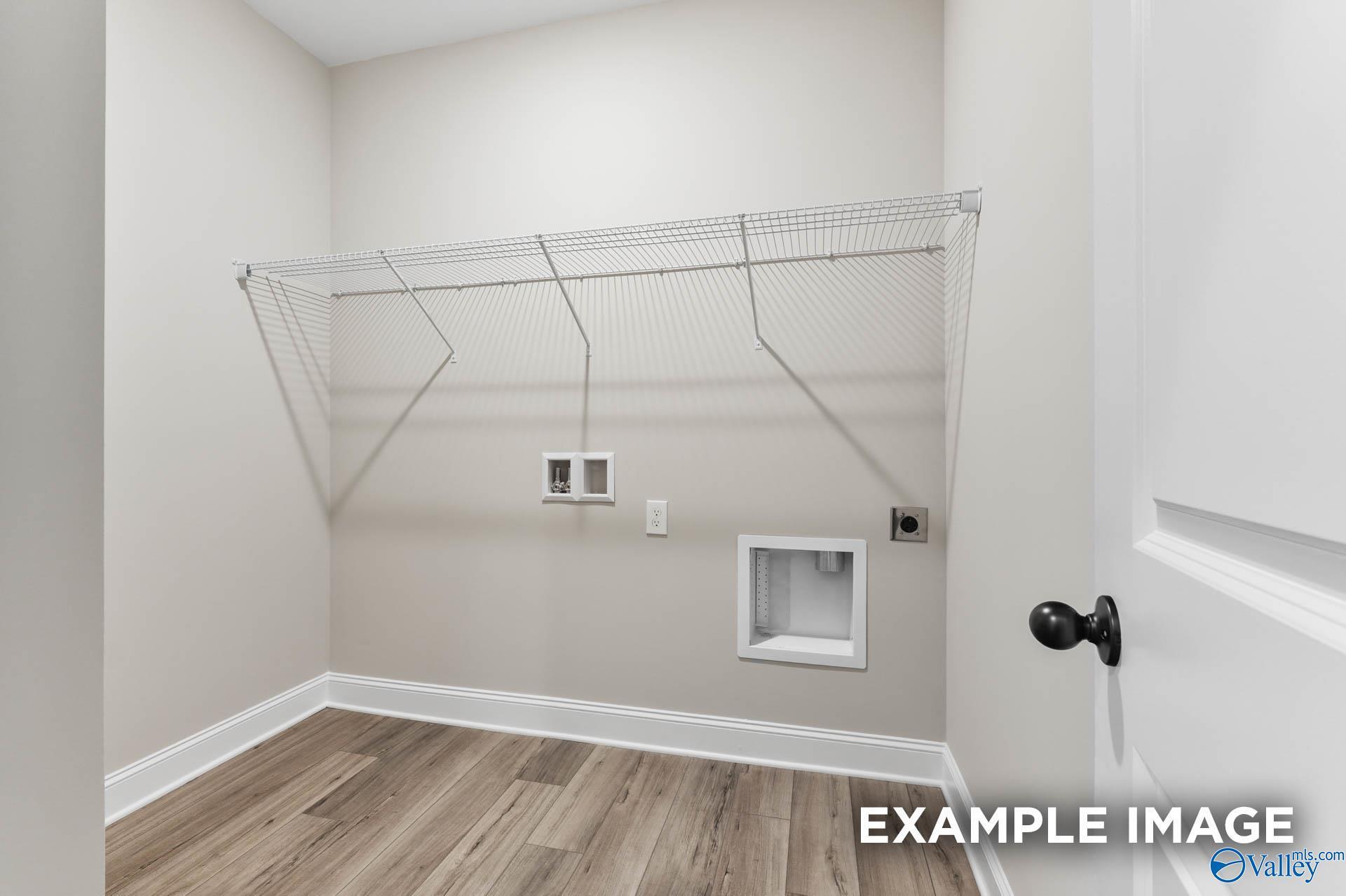 Spacious laundry room with wire shelving, washer/dryer hookups and beige walls in Davidson Homes The Daphne C, Athens, AL