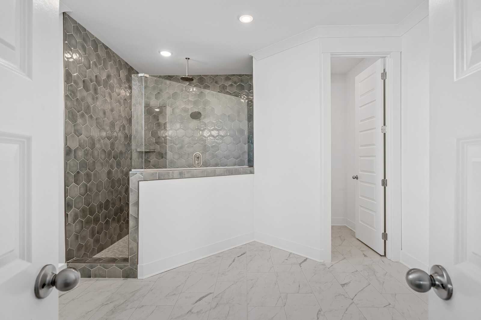Elegant master bathroom with gray hexagonal tile walk-in shower and glass door in Davidson Homes The Hawkins, Murfreesboro, TN