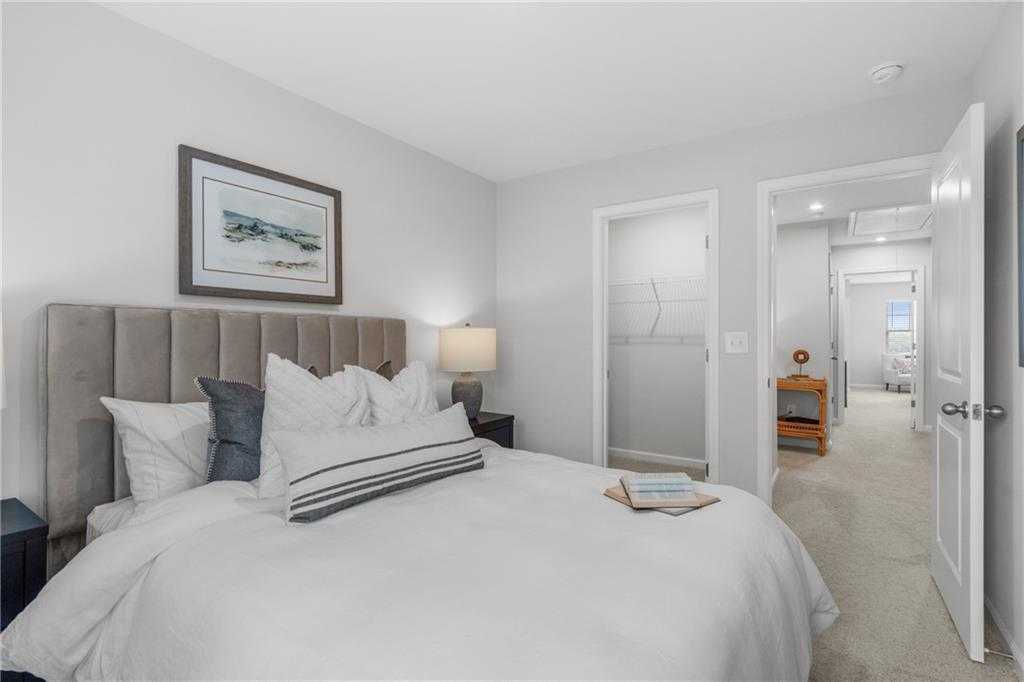 Cozy bedroom with gray upholstered headboard bed, white linens, and seascape art in Davidson Homes The Durant A, Emerson, GA