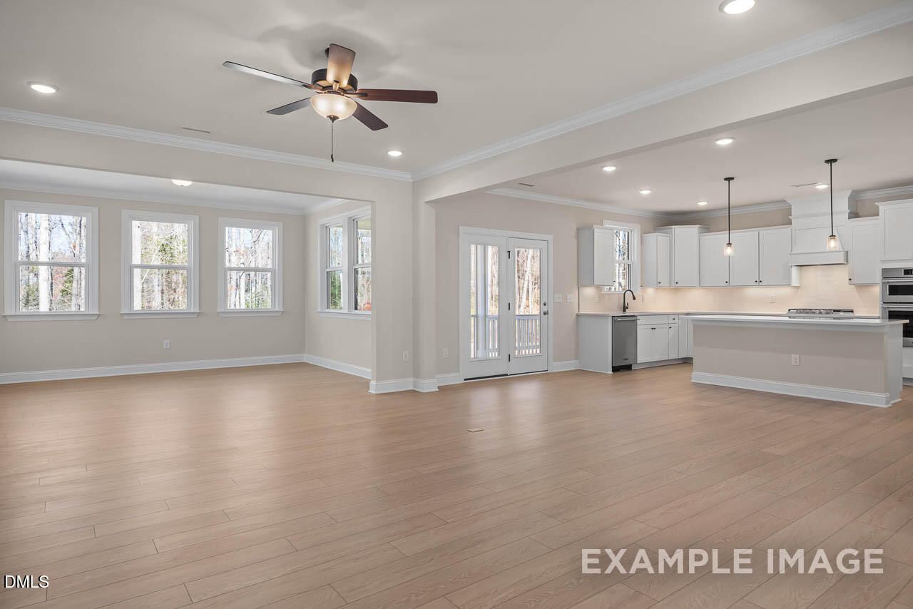 Open-concept living room and kitchen with hardwood floors, white cabinets, island, and French doors in 4-bedroom Davidson Homes Crawford D, Angier, NC