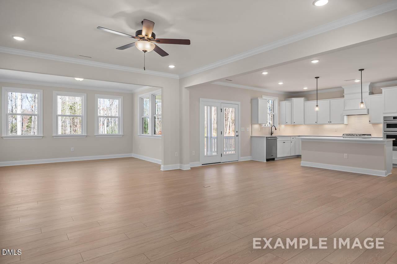 Open-concept living room and kitchen with hardwood floors, white cabinets, island, and French doors in 4-bedroom Davidson Homes Crawford D, Angier, NC