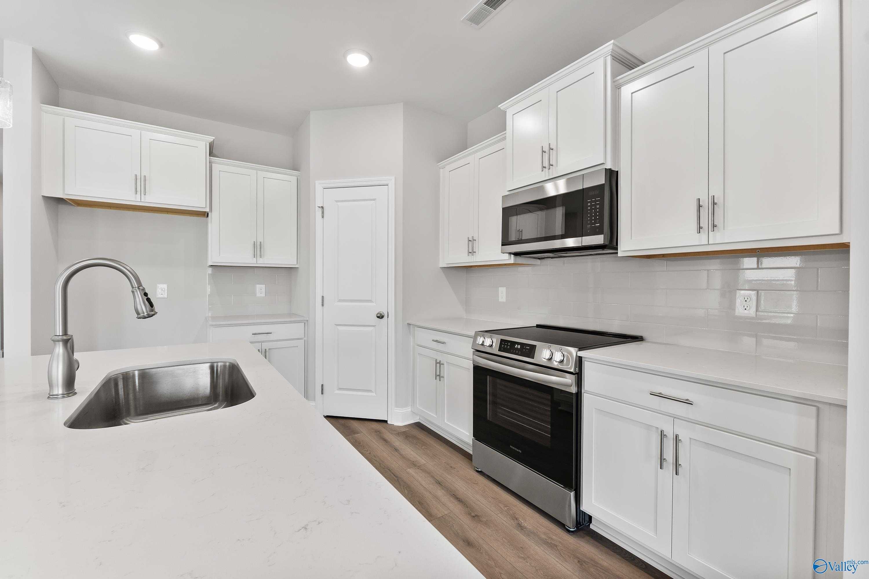 Bright modern kitchen with white shaker cabinets, stainless steel appliances, and quartz island in Davidson Homes The Franklin C