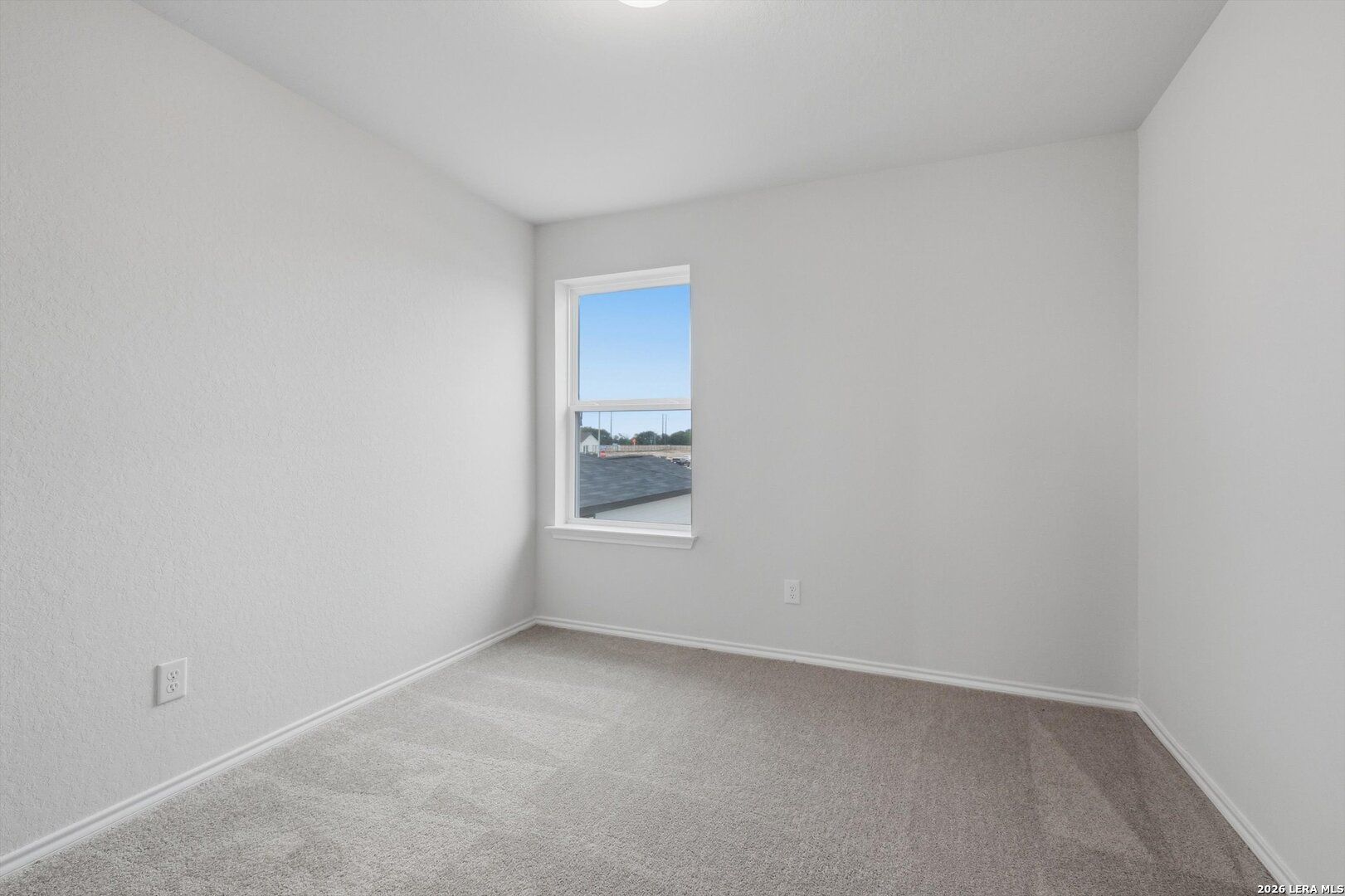 Empty bedroom with white walls, beige carpet, large window overlooking construction in Davidson Homes The Blanco C, San Antonio