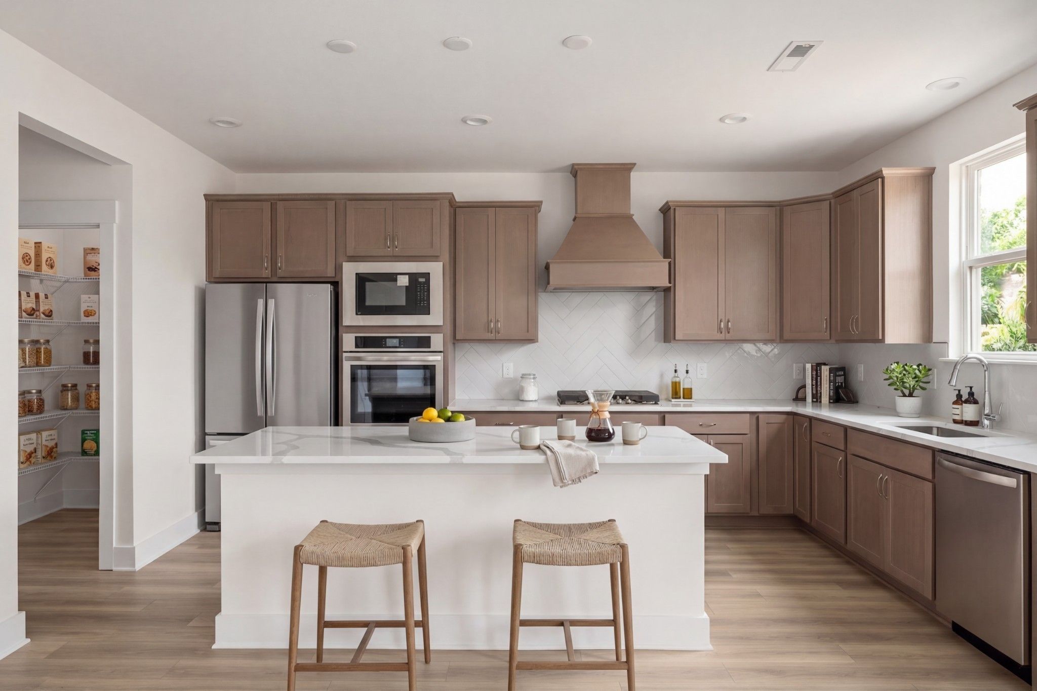 Modern kitchen with white island, herringbone backsplash, and walk-in pantry in The Henry C floor plan, Mt. Juliet, TN.