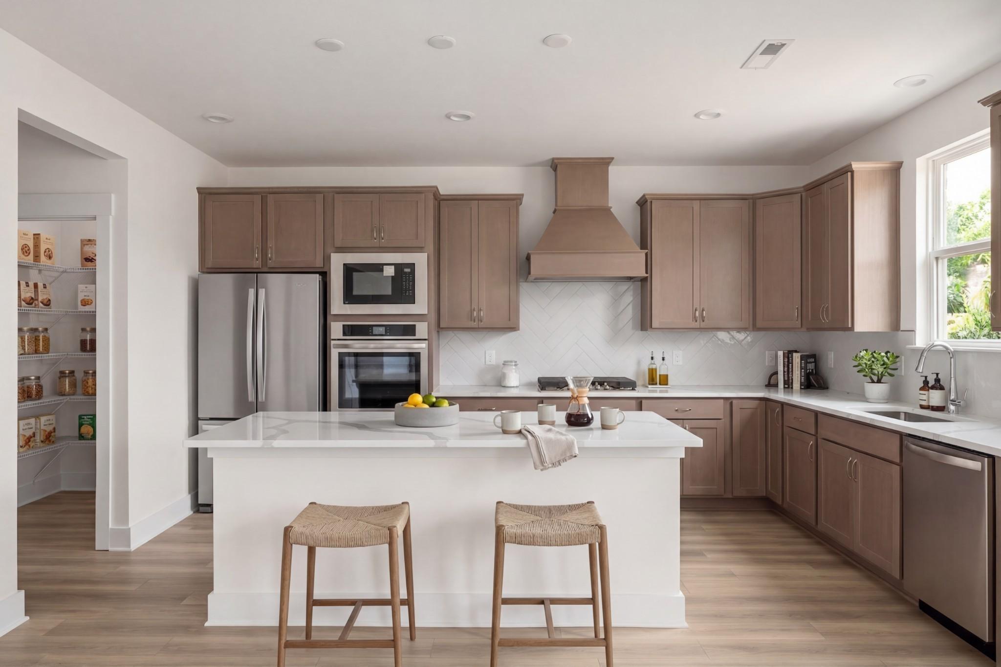 Modern kitchen with white island, herringbone backsplash, and walk-in pantry in The Henry C floor plan, Mt. Juliet, TN.