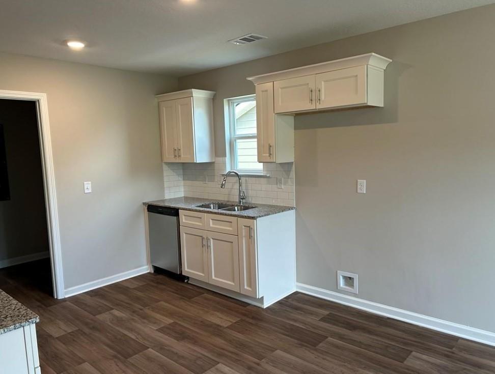 Modern kitchen featuring white cabinets, subway tile backsplash, stainless sink, and wood floors in The Washington by Davidson Homes, Phenix City, AL