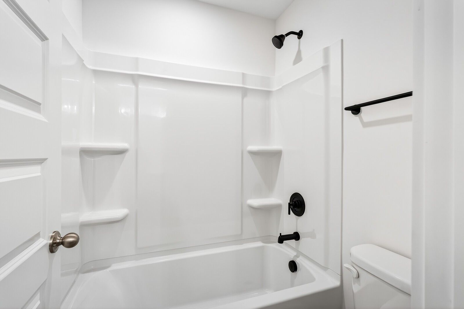 Modern white bathroom featuring deep soaking tub, glass-enclosed shower, and sleek black fixtures in Ridgeport C home, Gallatin, TN