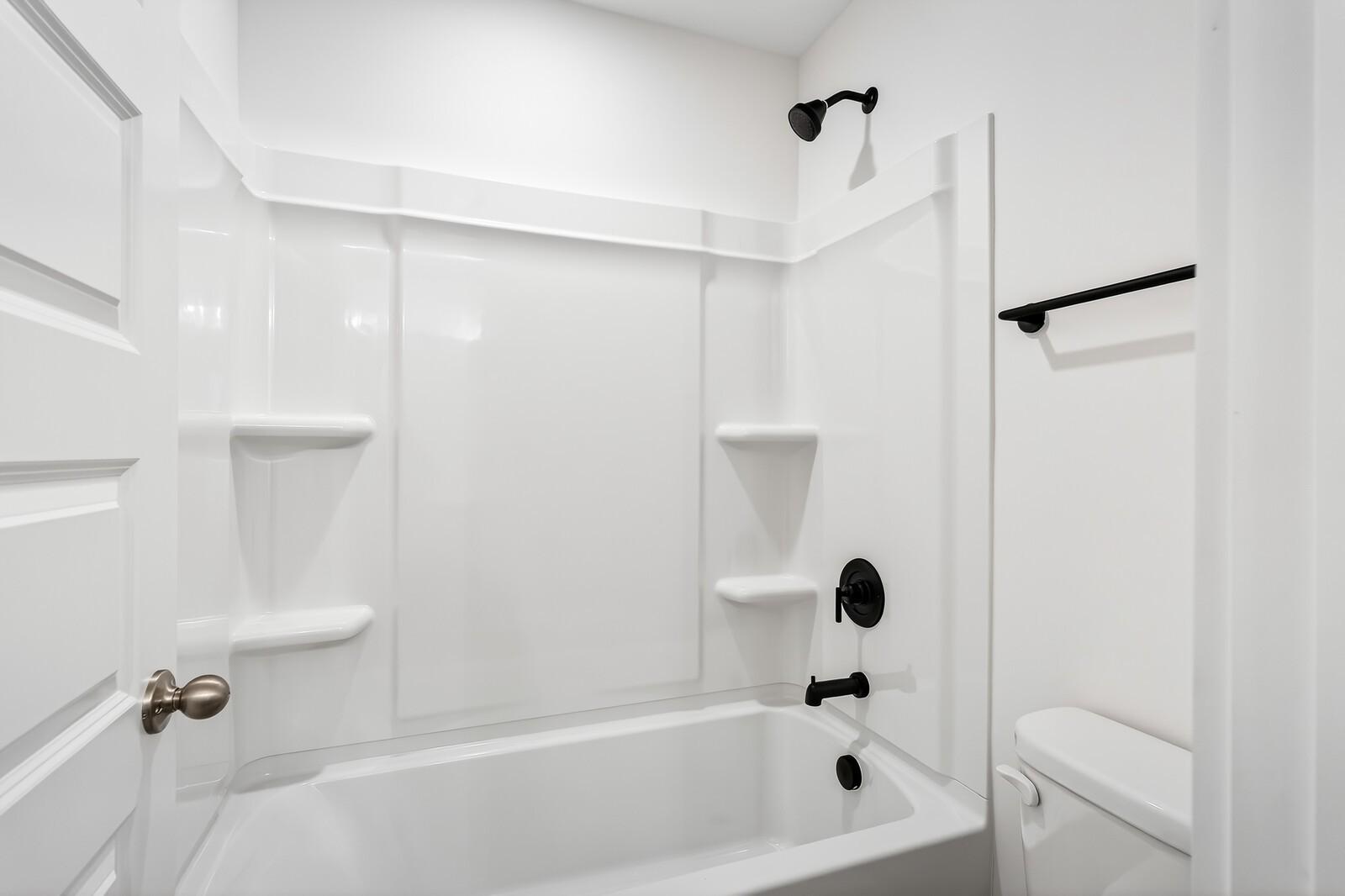 Modern white bathroom featuring deep soaking tub, glass-enclosed shower, and sleek black fixtures in Ridgeport C home, Gallatin, TN