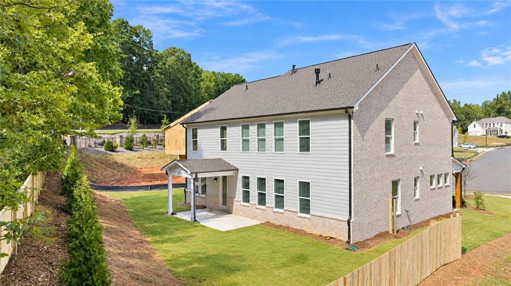 Two-story brick and siding home with covered patio and fenced backyard in Melody Lakeside Estates, Buford, Georgia.