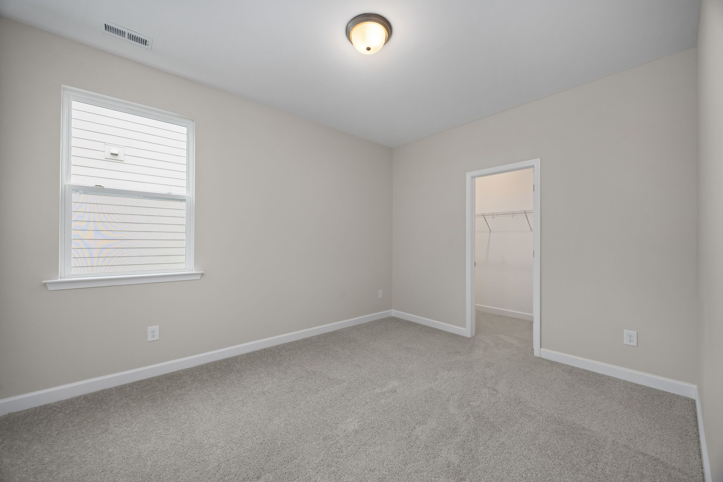 Spacious secondary bedroom in The Beech A with beige walls, gray carpet, large window blinds, ceiling light, and walk-in closet